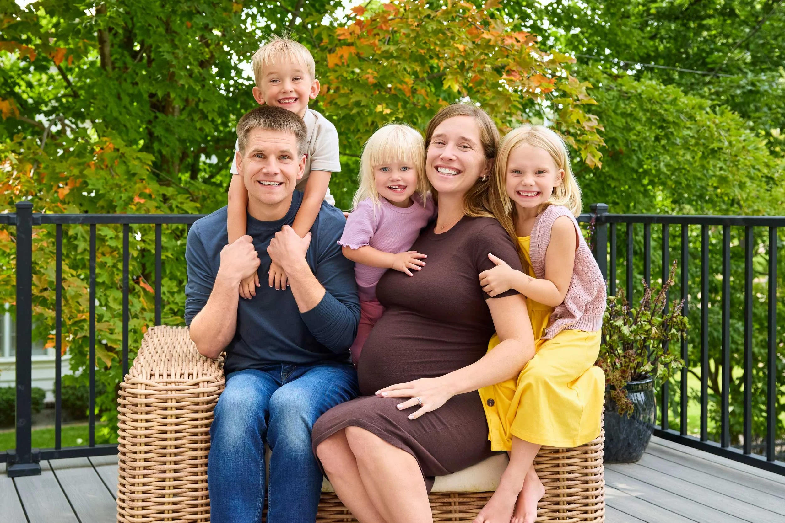 pregnant mom sits in chair, posing with smiling kids and husband - olive juice studios photographer in rochester mn