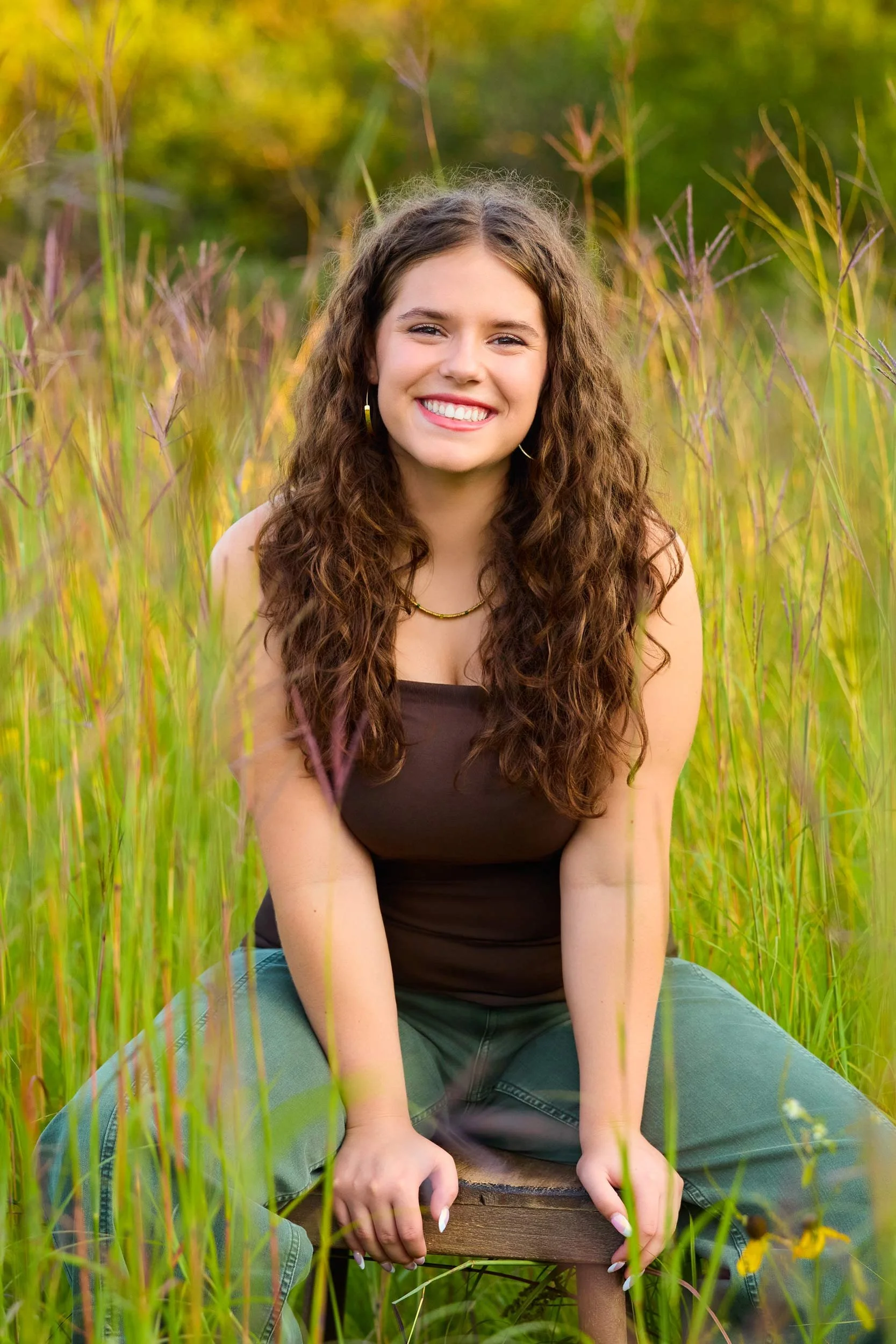 High school senior photo shoot in tall grass near Rochester MN during golden hour