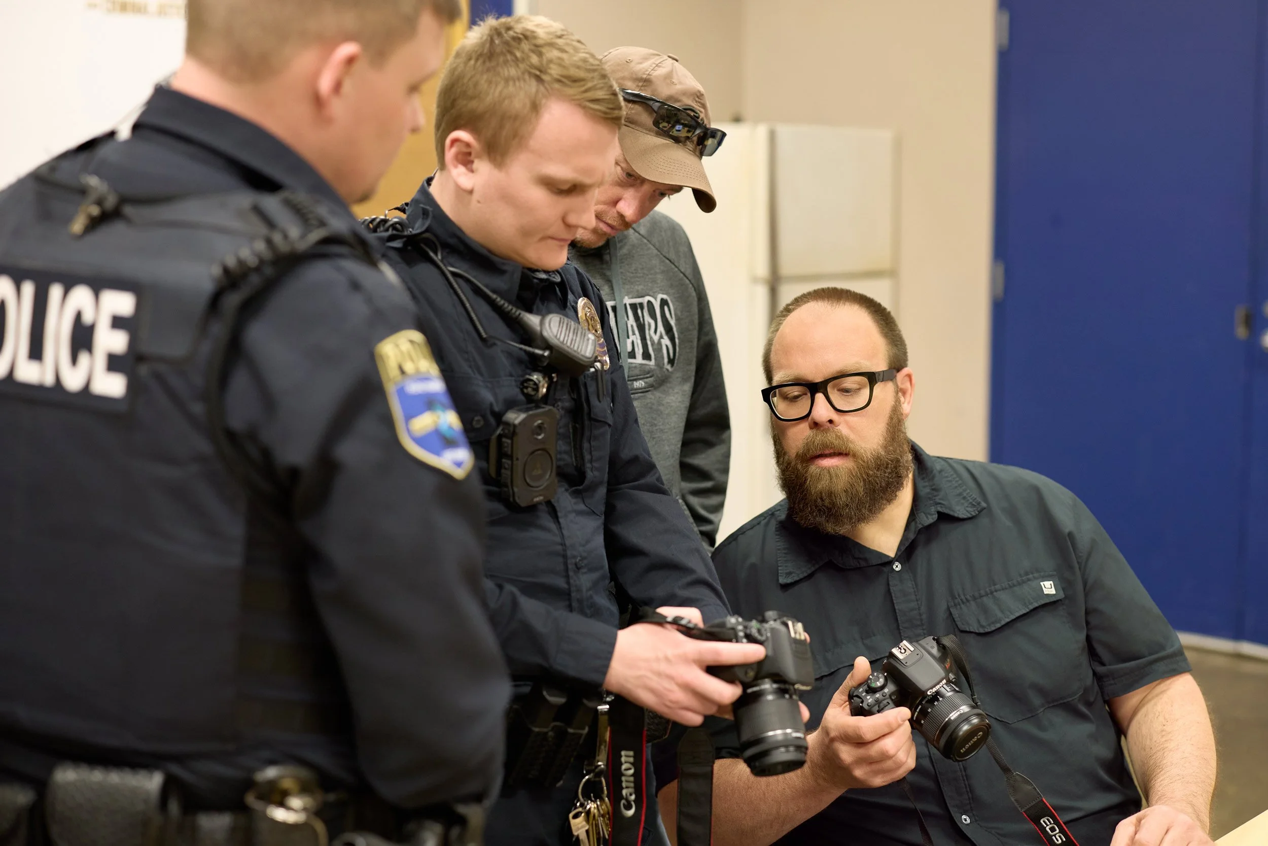 hree police officers showing Scott Schoeberl the back of their cameras during a hands-on crime scene photography class in Rochester, Minnesota