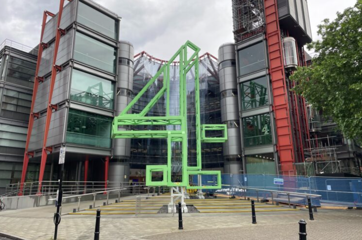An oversized green number four mural is photographed outside a large glass office building
