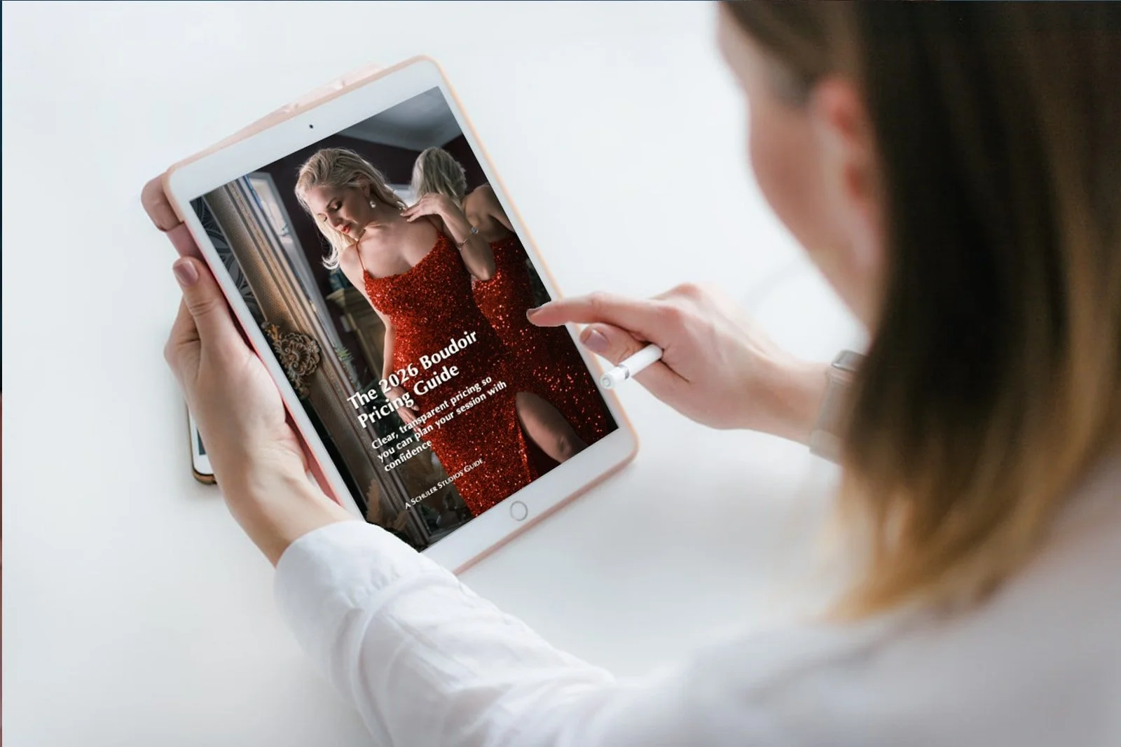 Woman holding a tablet computer displaying a downloaded copy of The Boudoir Pricing Guide