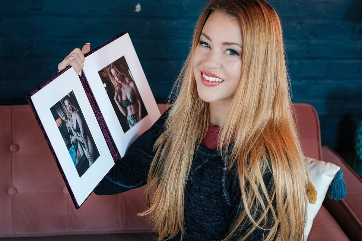 Boudoir client showing one of her boudoir photo products — a two-panel matted folio for her nightstand.