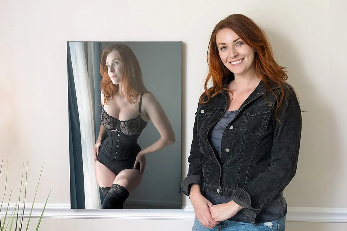 Woman standing beside her boudoir wall artwork.