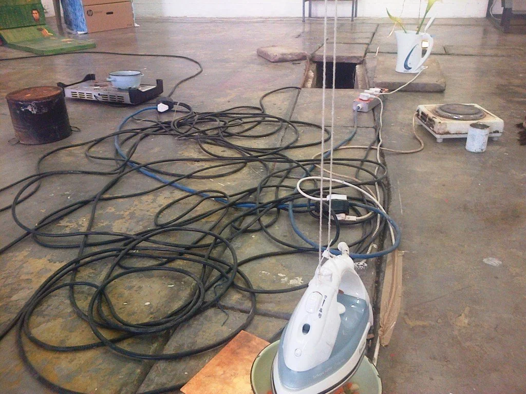 izinyoka (2013) installation detail (iron and enamel bowel with frozen vegetables, hot plate stoves and extension cords