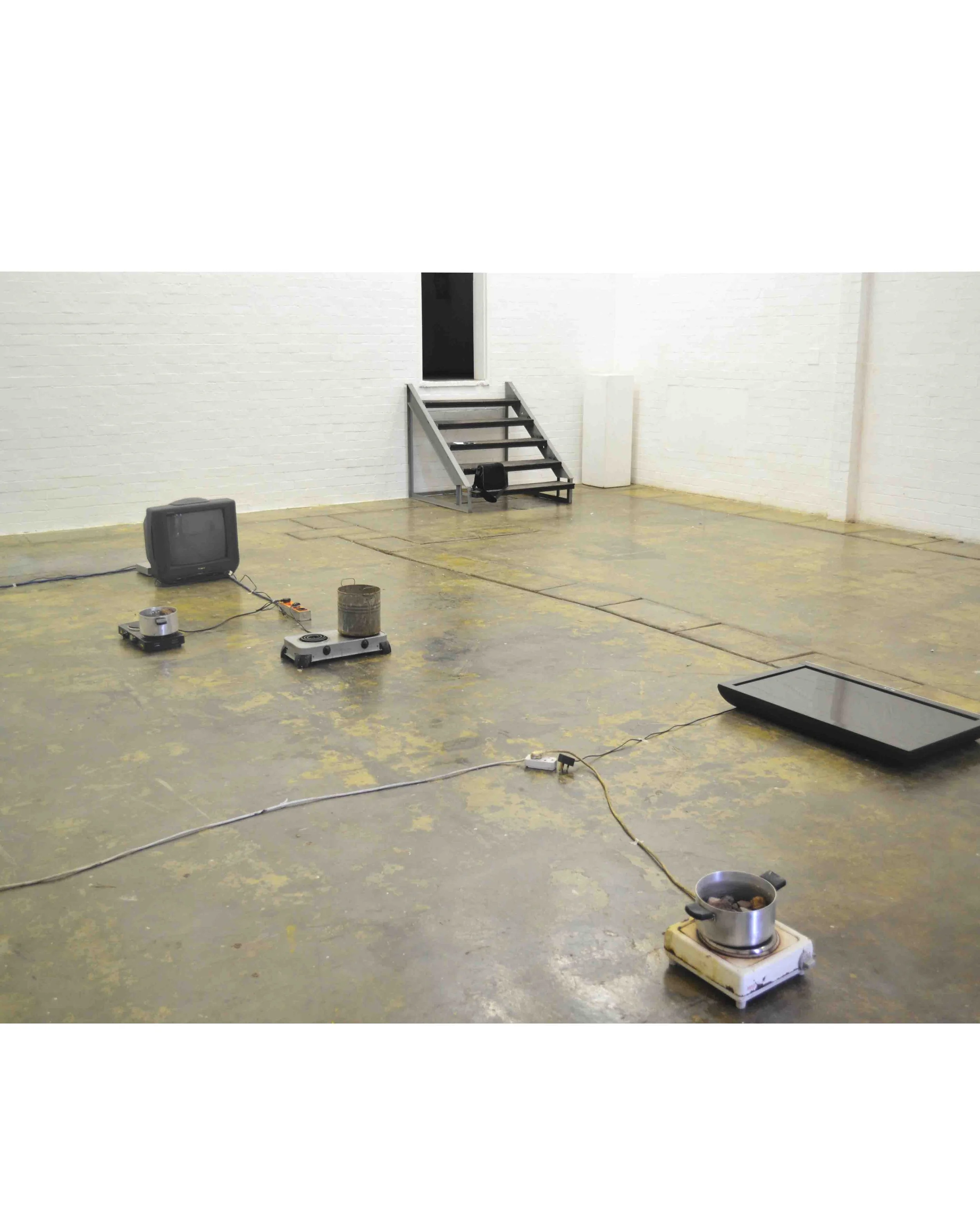 installation view of tv, boiling rocks on a hot plate stove