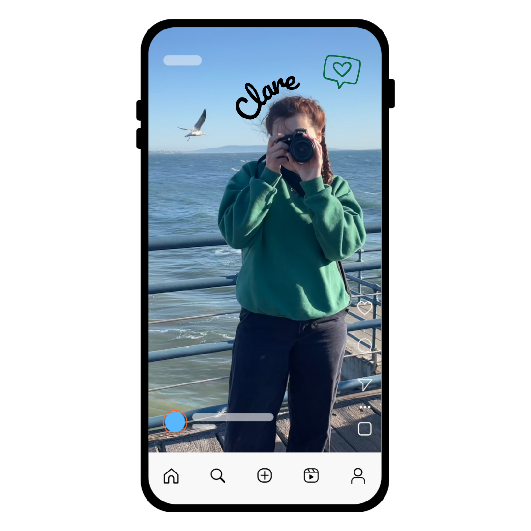 Person named Clare standing on a pier by the ocean, holding a DSLR camera to their face while photographing a seagull in flight, displayed inside a smartphone-style social media frame.