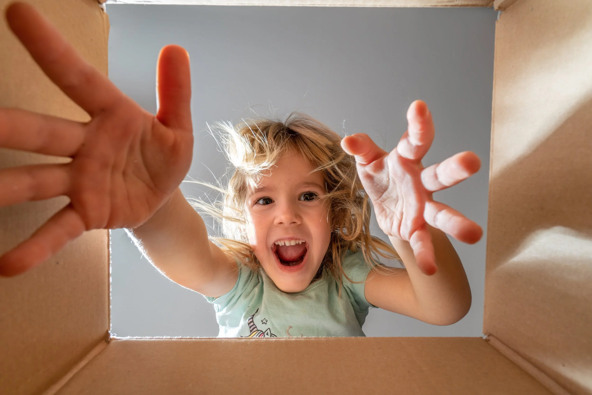 A little girl reaching into box.