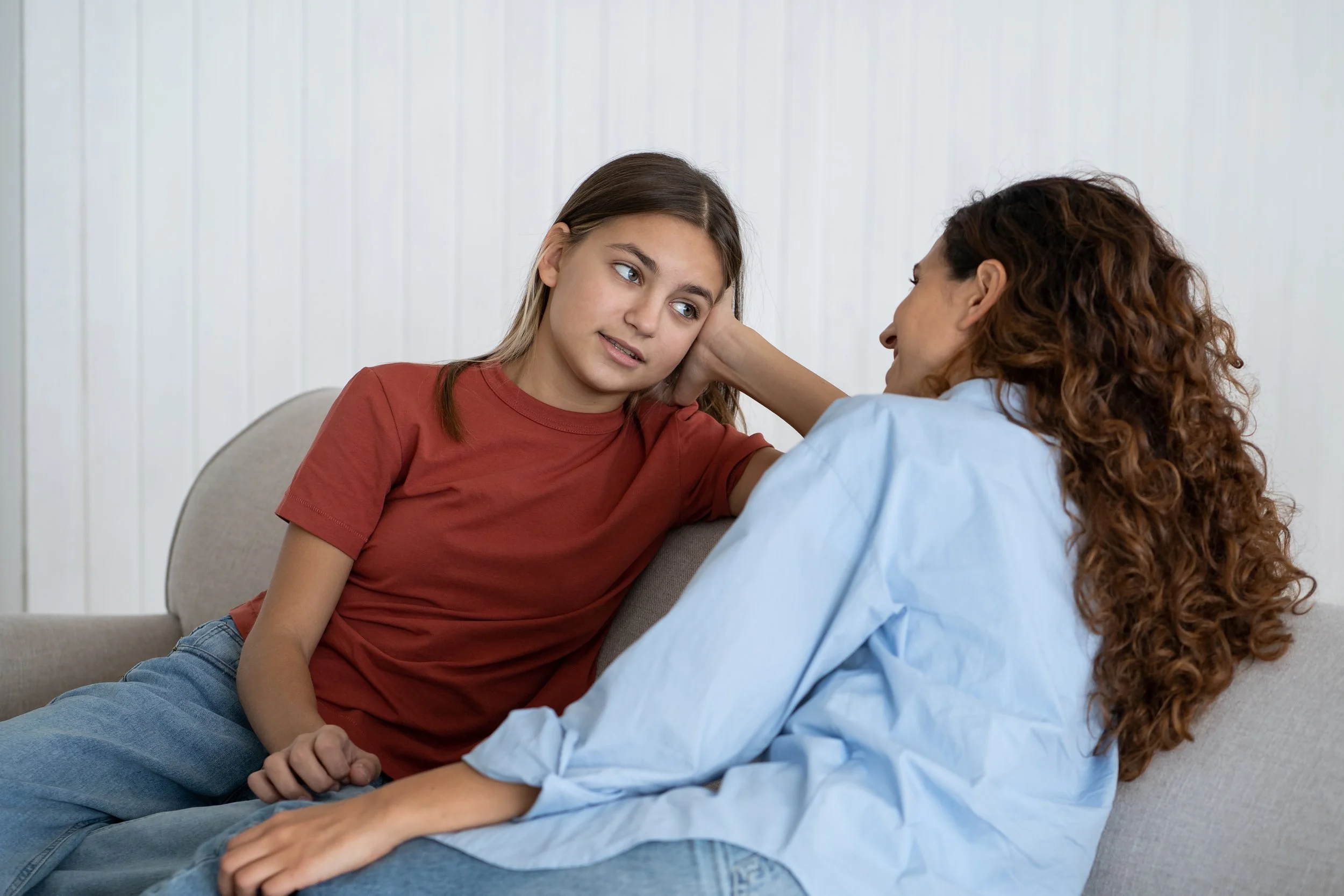 Two women talk on couch.