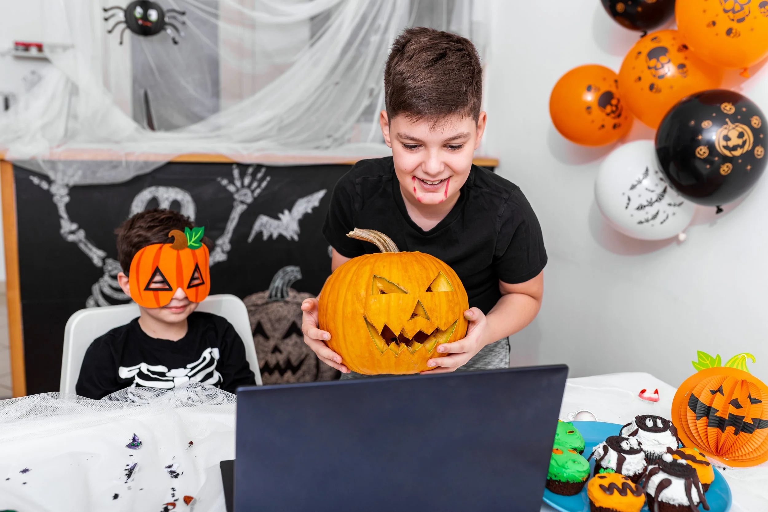 Two kids celebrate Halloween with pumpkins.