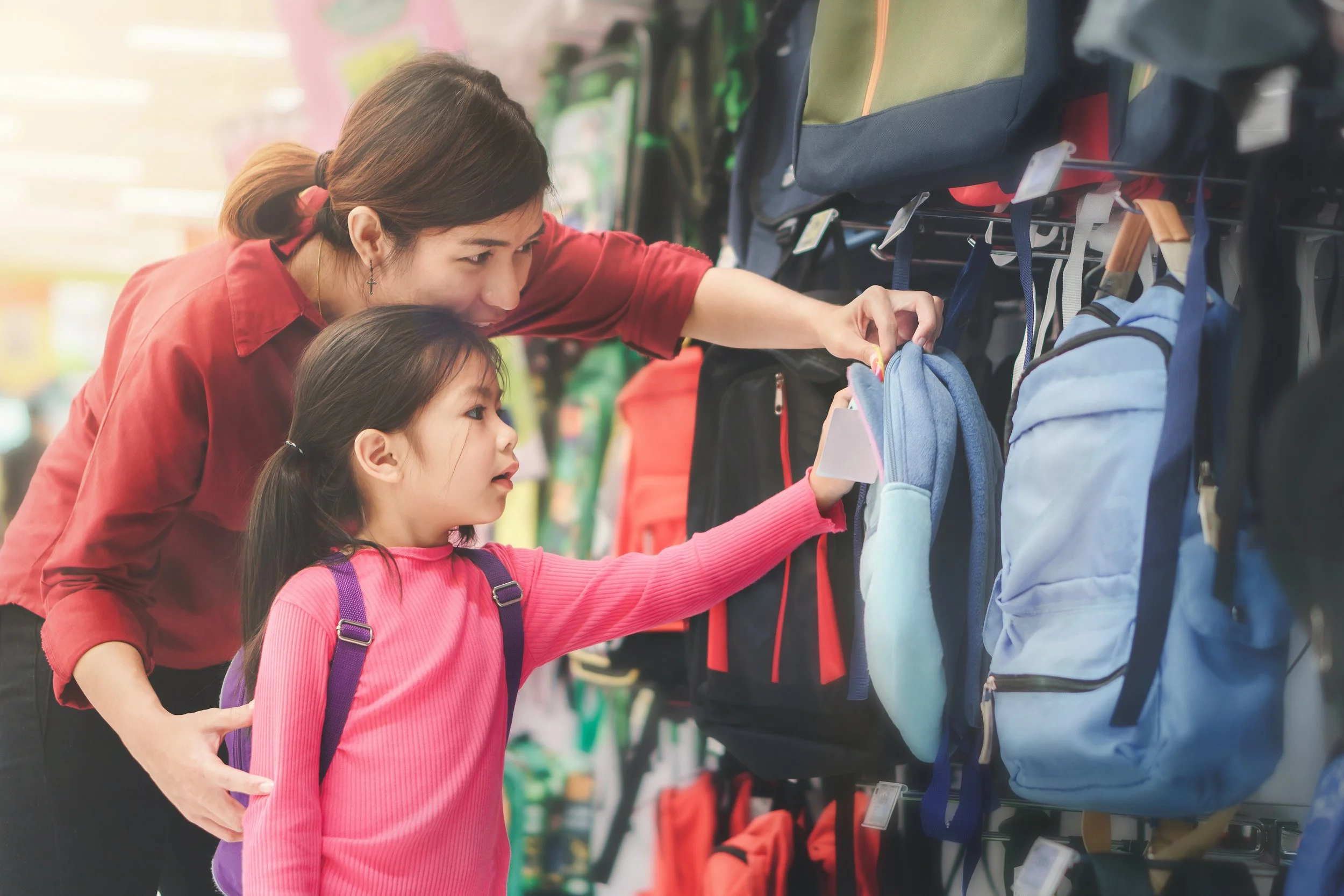 A child and their mother shop for a backpack.