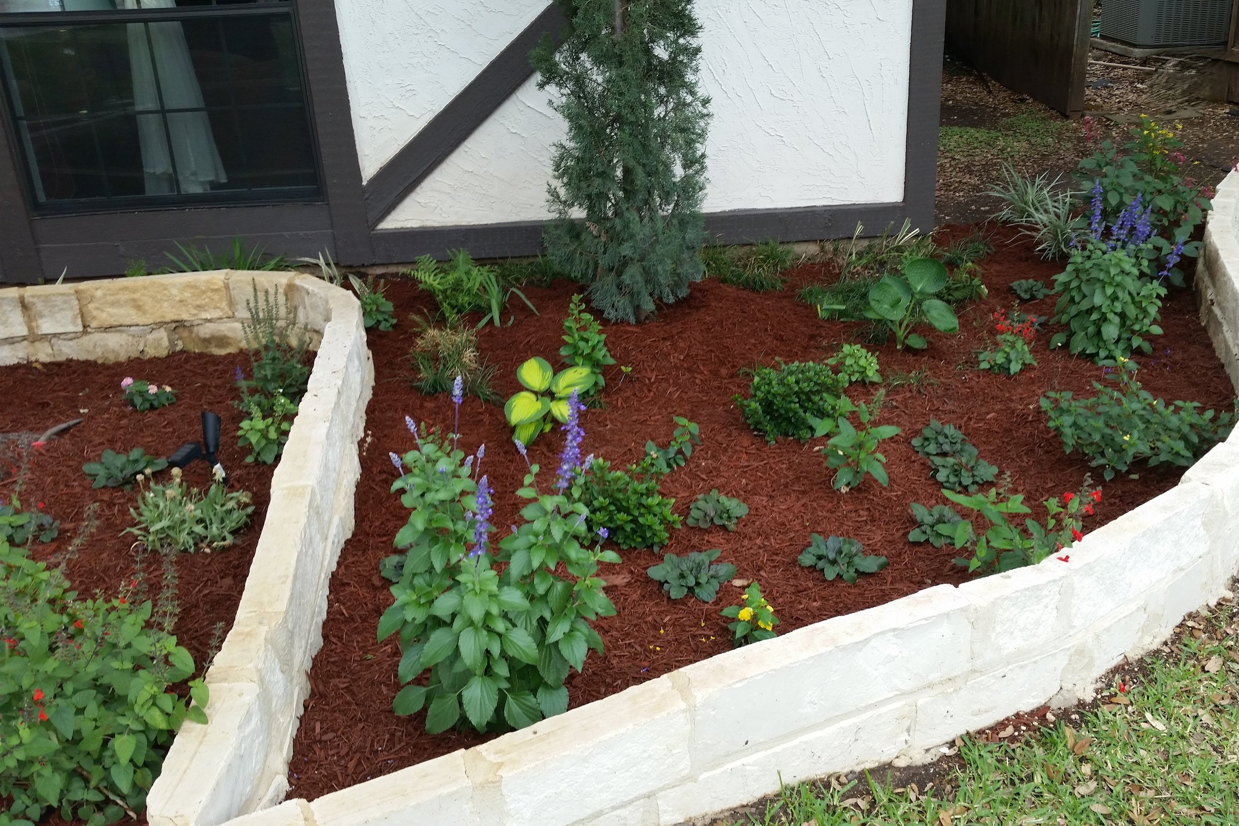 Brevarian Style Landscape Bed With Limestone Chop Block and Red Mulch
