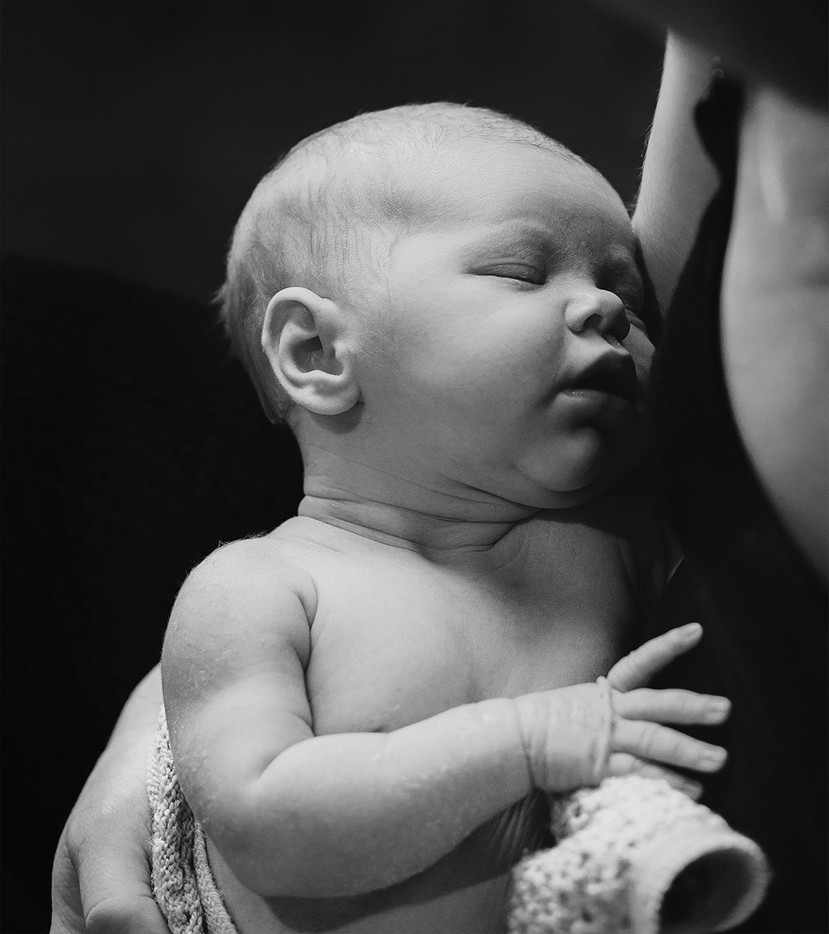 Søvnende baby som blir holdt av en voksen, svart-hvitt bilde