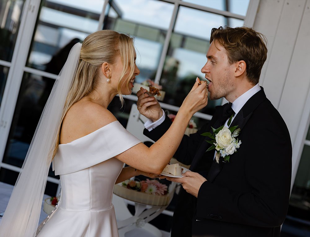 Brudepar som feirer bryllup, der bruden gir kake til brudgommen.