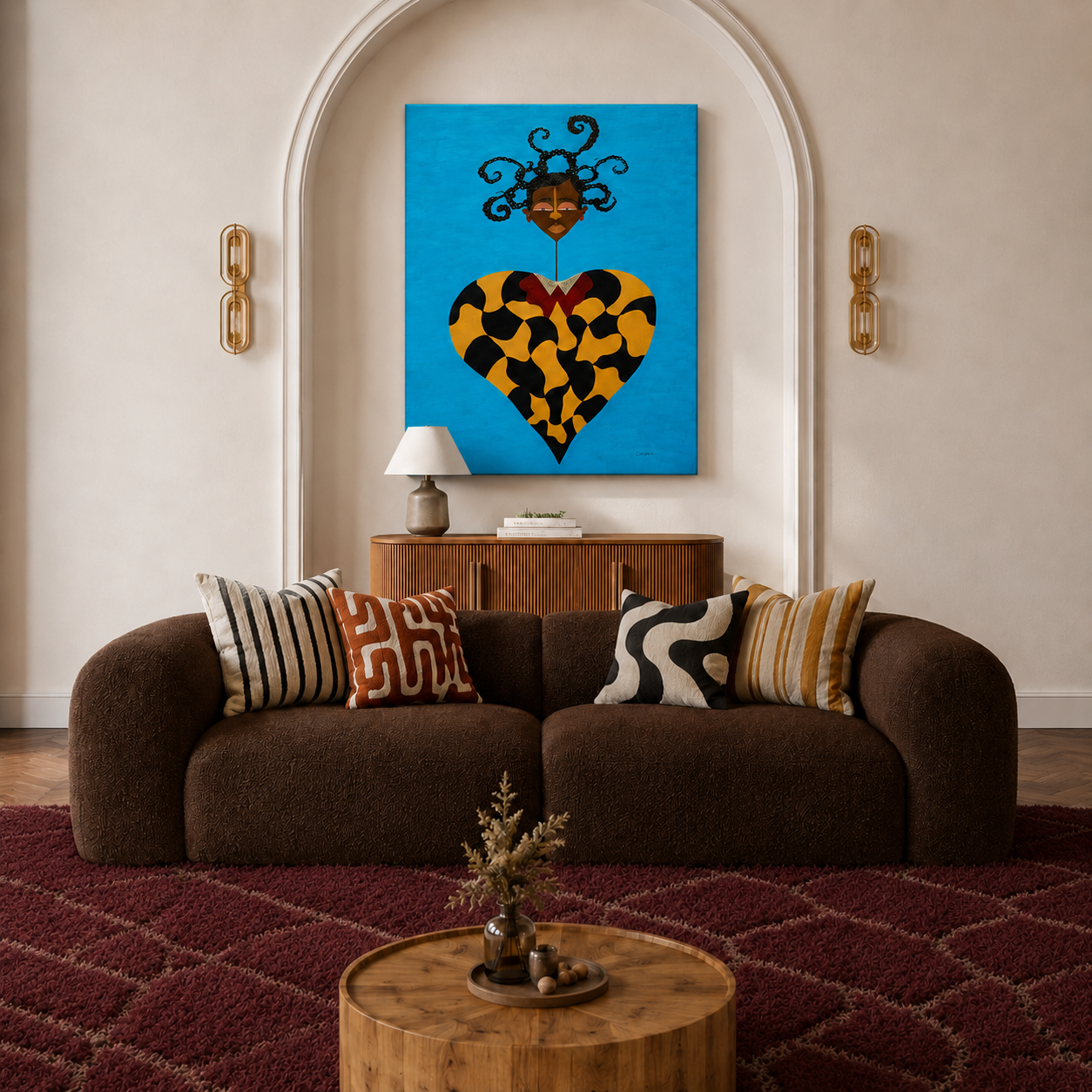 Living room with a dark brown couch, striped and patterned throw pillows, a red textured rug, a round wooden coffee table with a small vase of dried flowers, a wooden sideboard with a table lamp and books, a large colorful portrait of a woman with cu