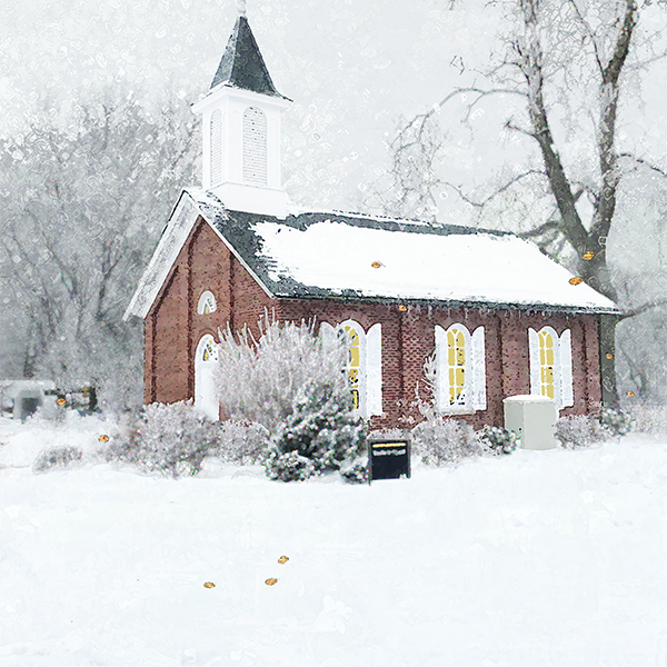 A small brick church with a white steeple and yellow windows surrounded by snow.