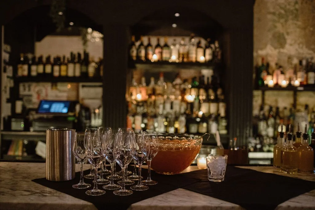 punch bowl and wine glasses sitting on top of the bar