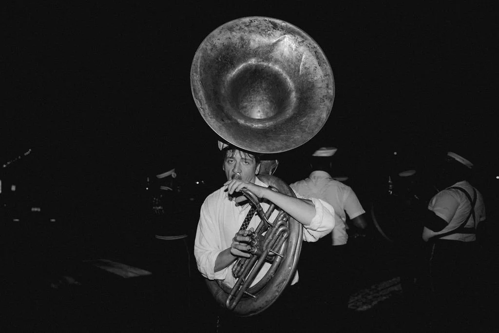 man wearing a white shirt holding the tuba