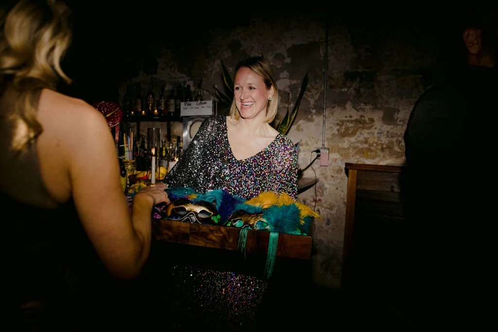 woman in s sparkly dress passing out mardi gras decorations
