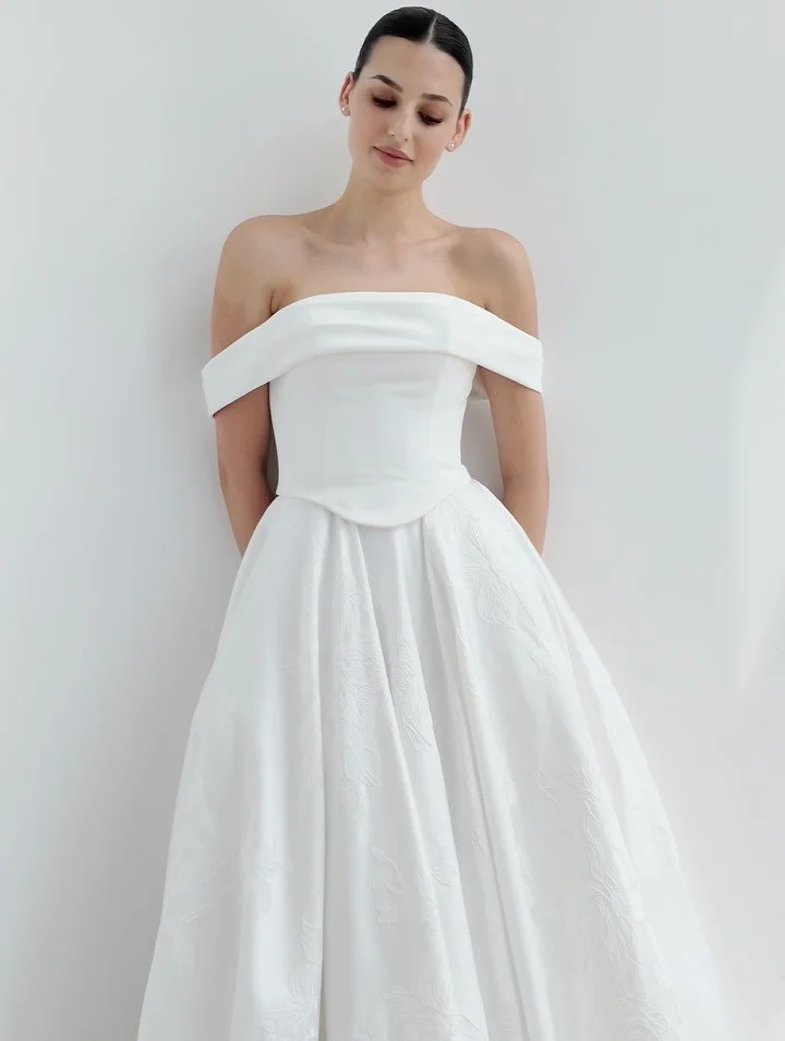 A separates combo that just makes sense 🤍

Featuring a pleated band neckline and a Basque waist, the SS1005 bodice stuns with its complementary off-the-shoulder sleeves. Paired with the SS1008 skirt, a brocade A-line silhouette featuring wide-cut pa