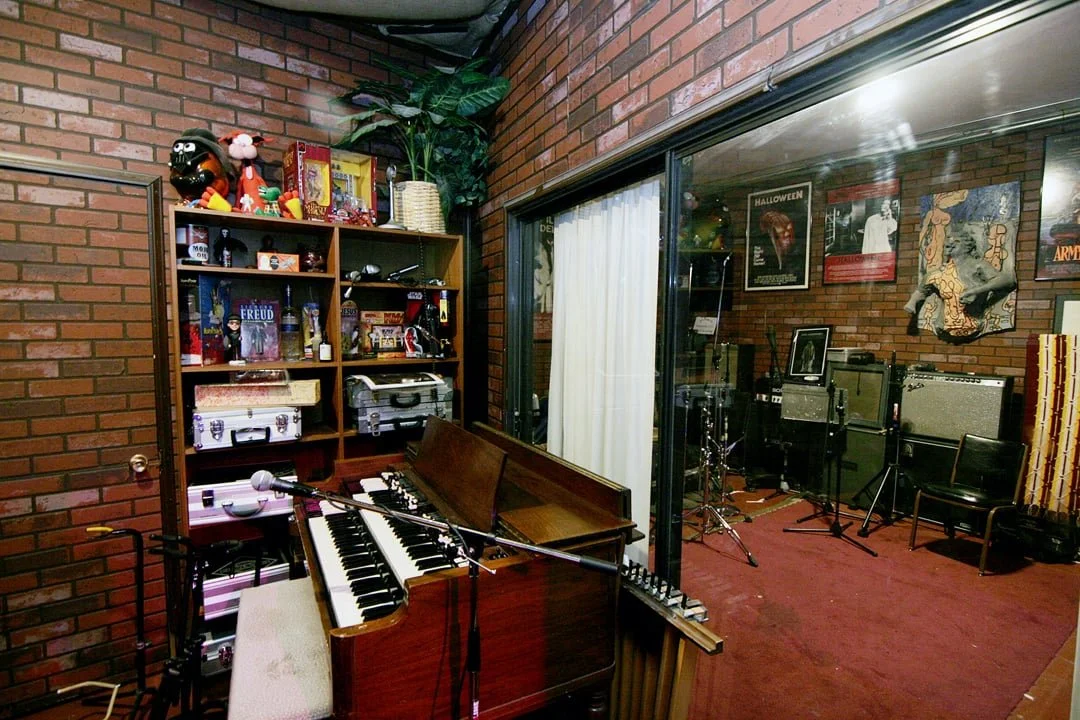Music studio with a piano, microphones, guitars, amps, and Halloween-themed decorations.