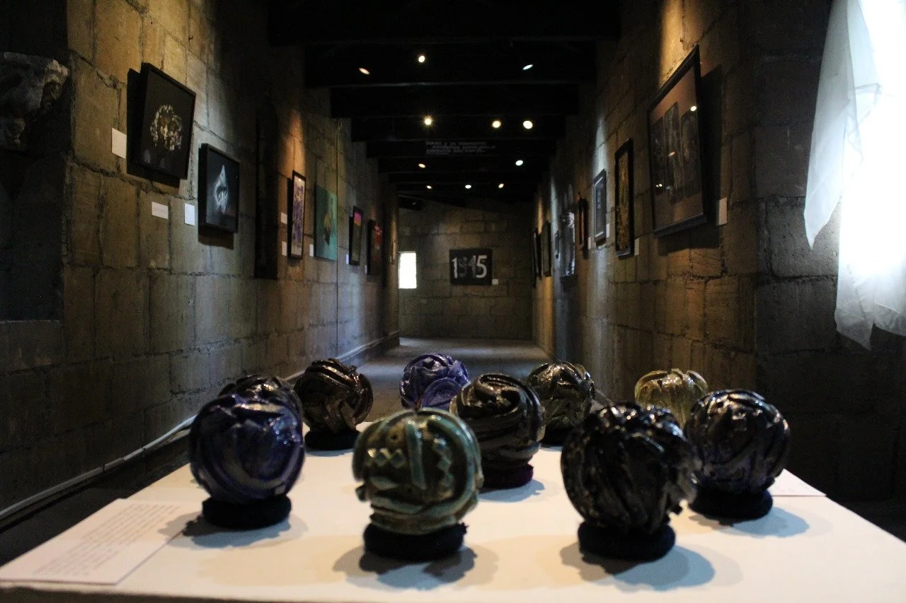 Vista de una galería de arte con esculturas esféricas y cuadros en las paredes.