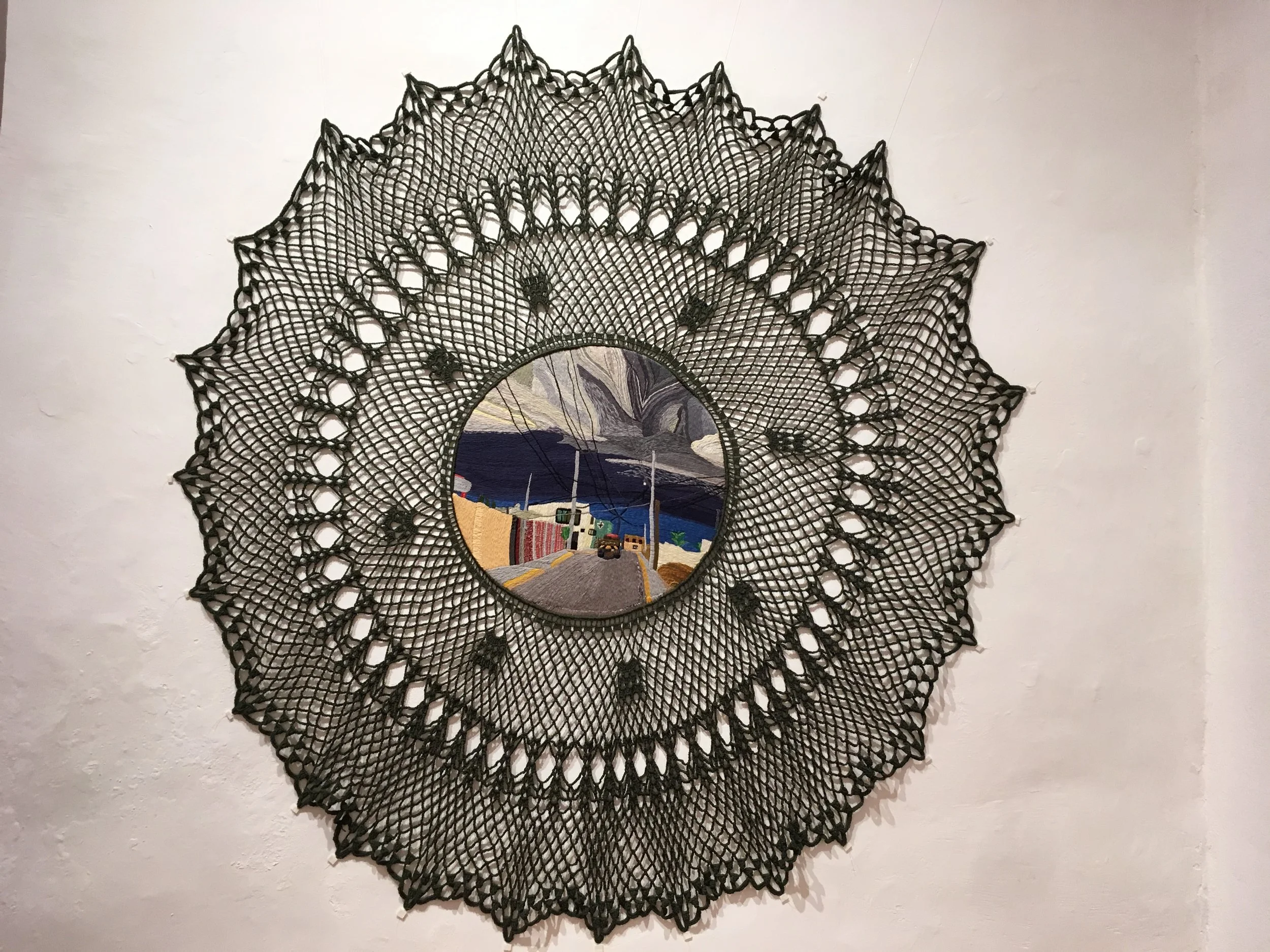 Tapiz circular tejido con diseño colorido de paisaje urbano en el centro.