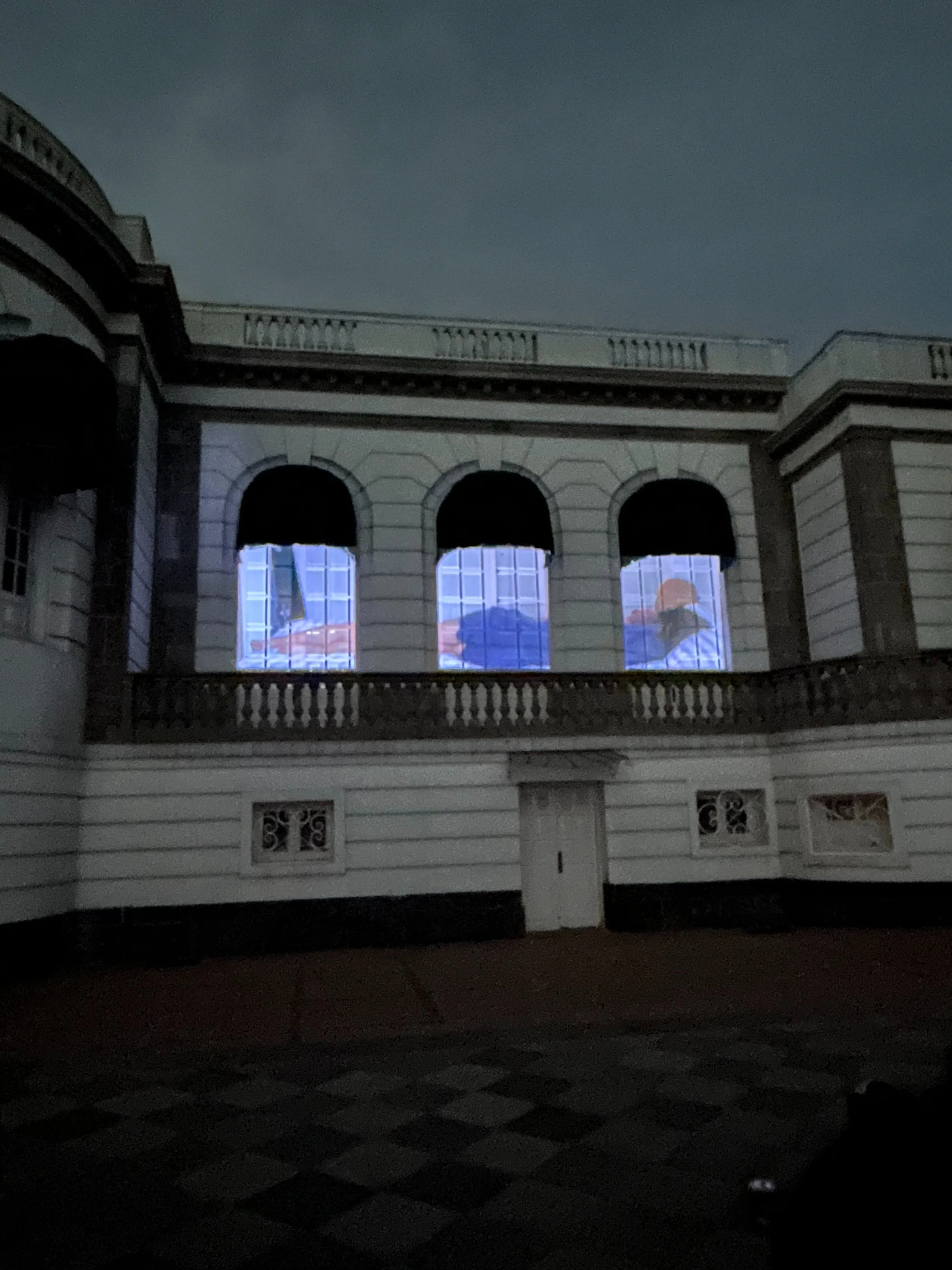 Edificio con arquitectura clásica y ventanas iluminadas por proyecciones.