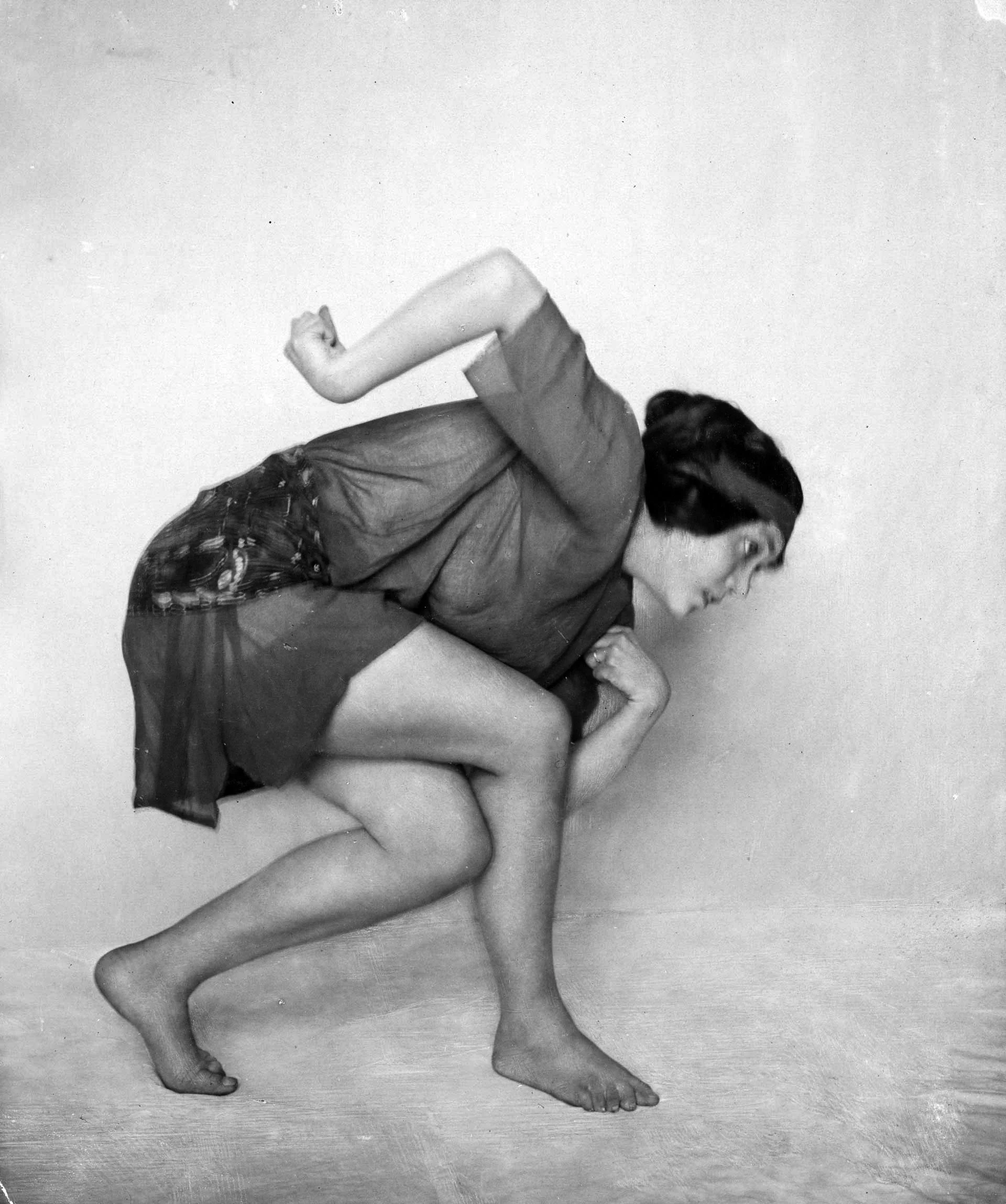 Una persona bailando descalza con una pose dinámica, vestida con ropa suelta.