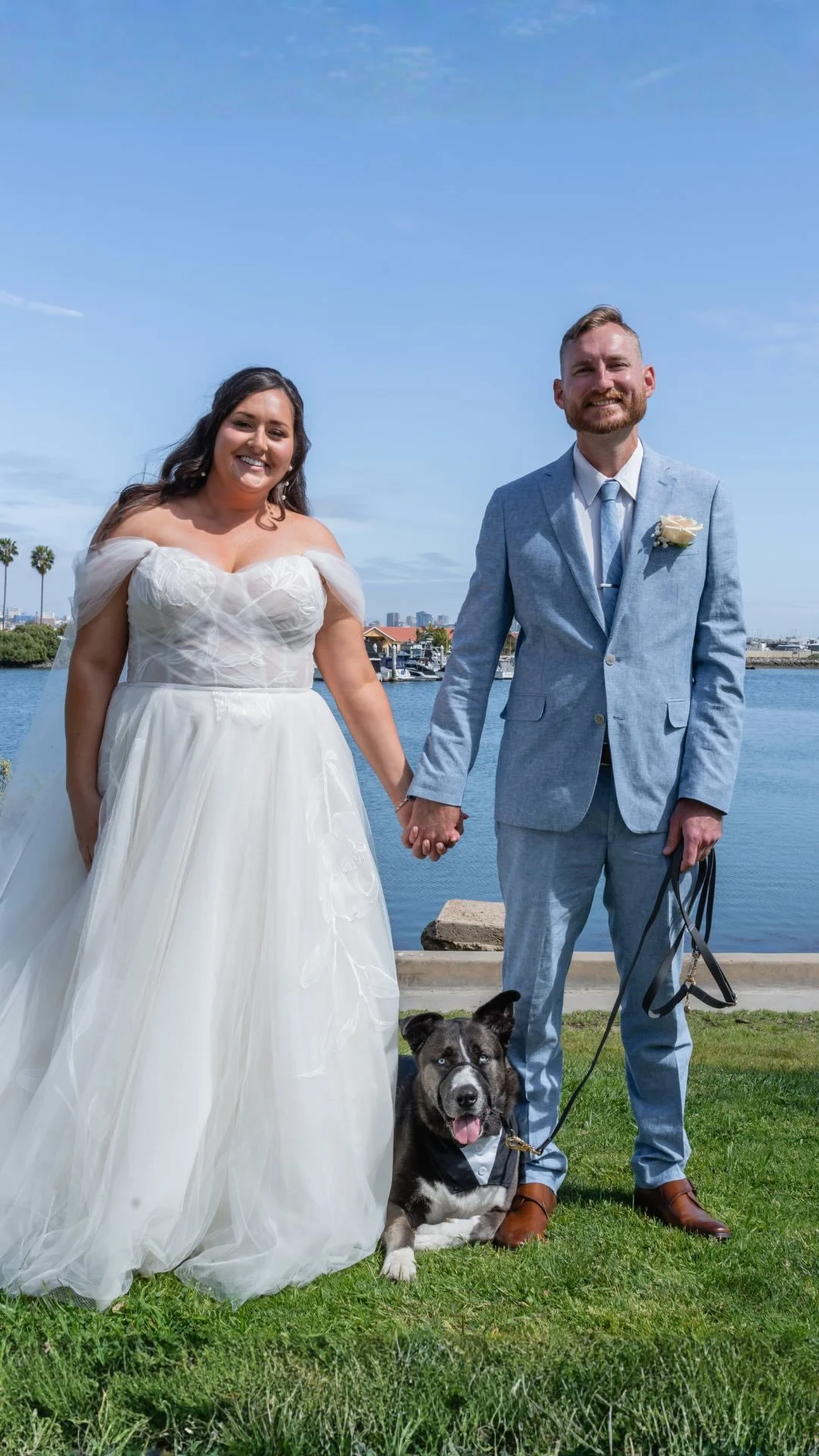 A bride and groom pose with their dog at a San Diego wedding
