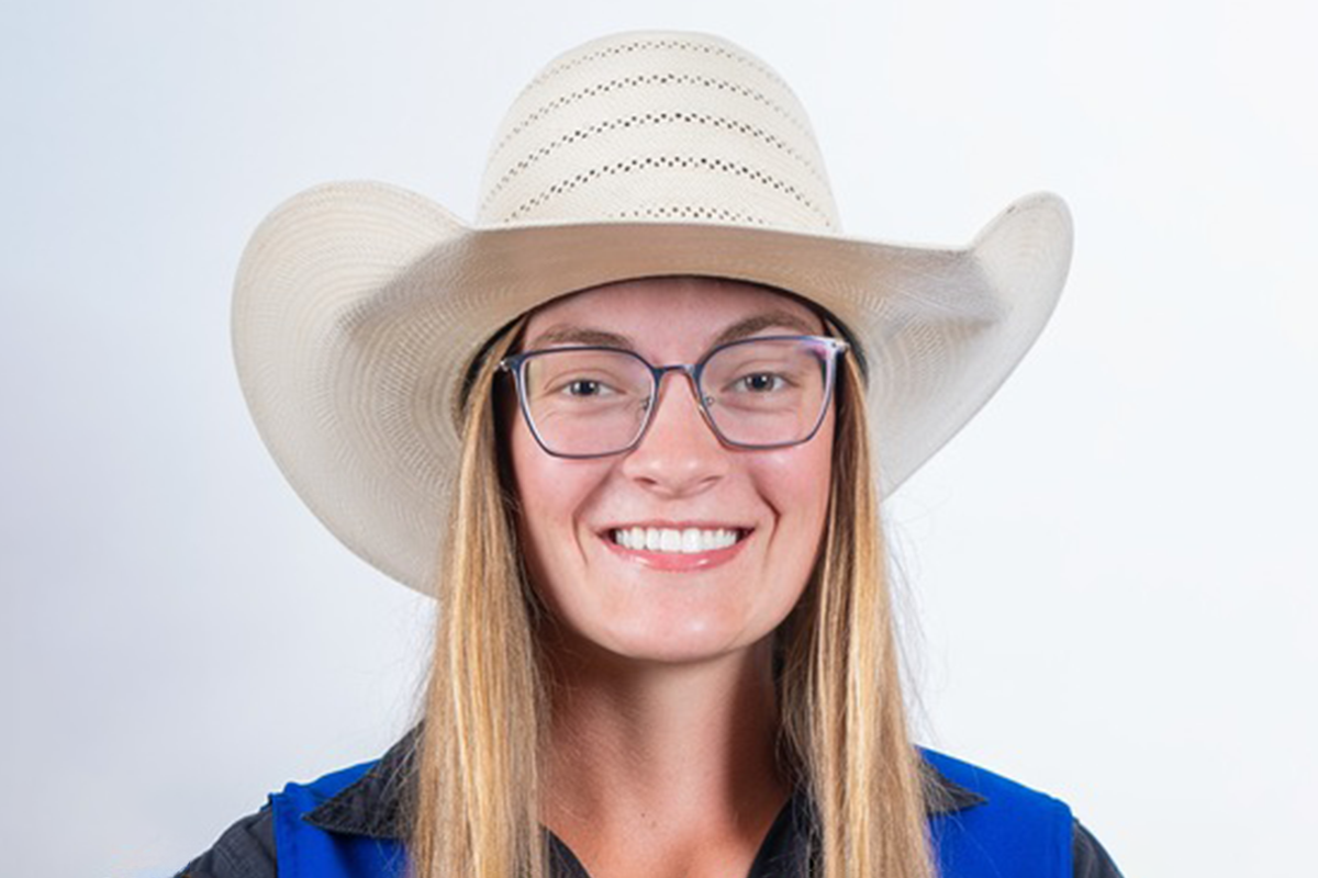 Young woman smiling wearing glasses and a wide-brimmed straw hat.