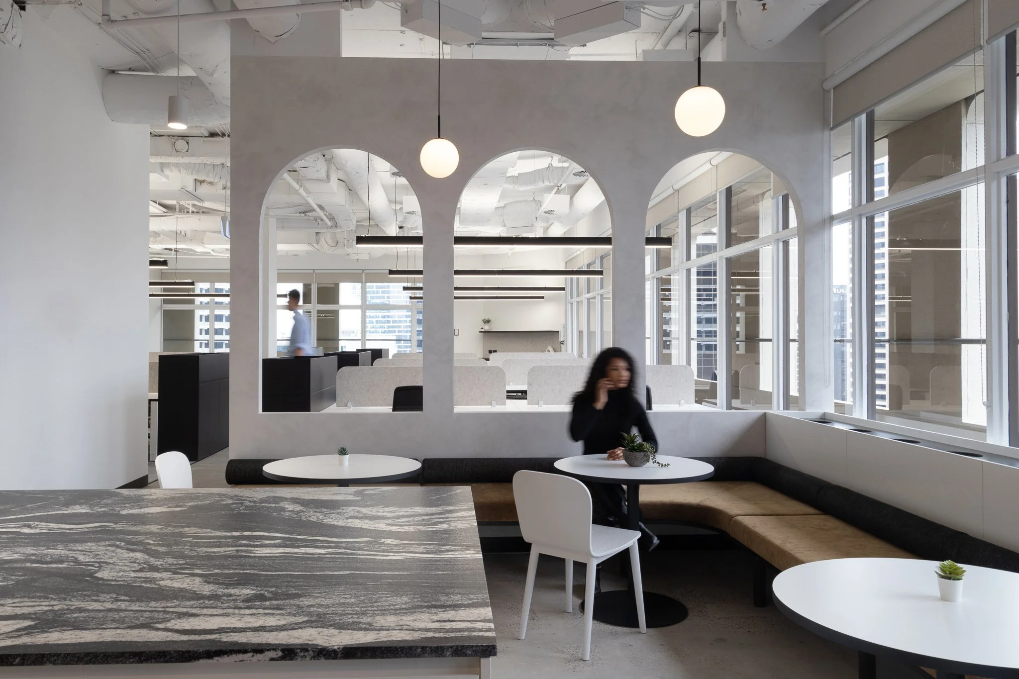 A unique seating area features a partial wall seprating different zones and a woman talking on the phone