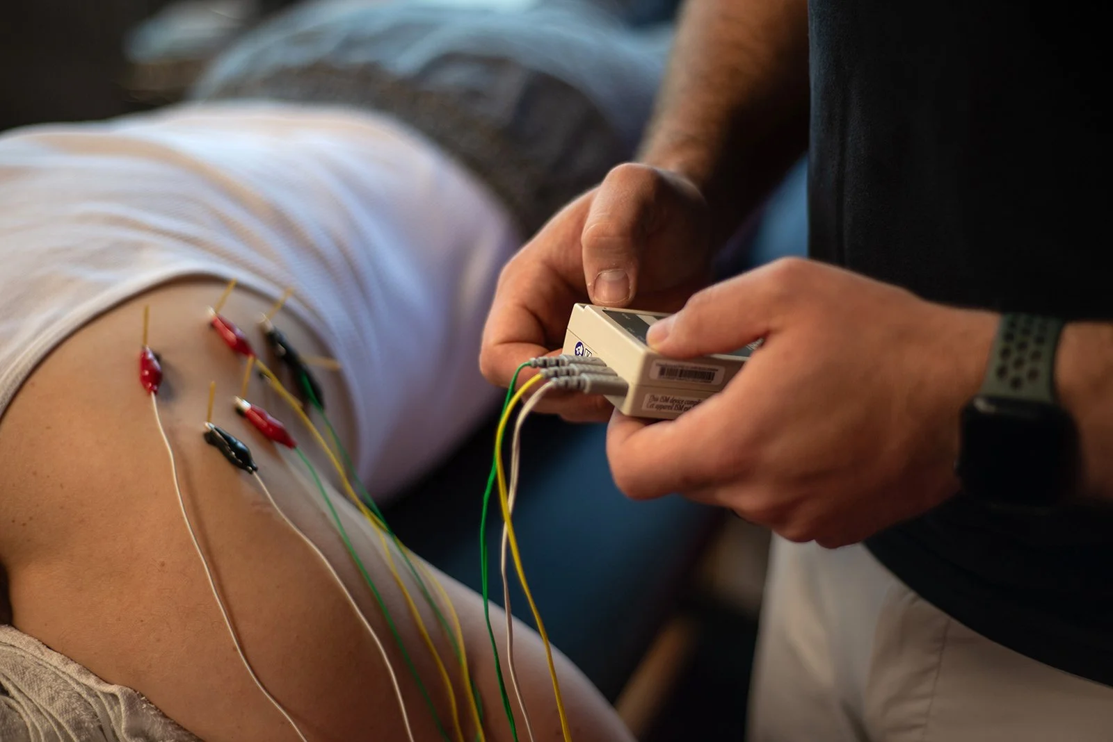 A person undergoing an electroencephalogram (EEG) test with electrodes attached to their scalp, while a technician adjusts or monitors the EEG device.