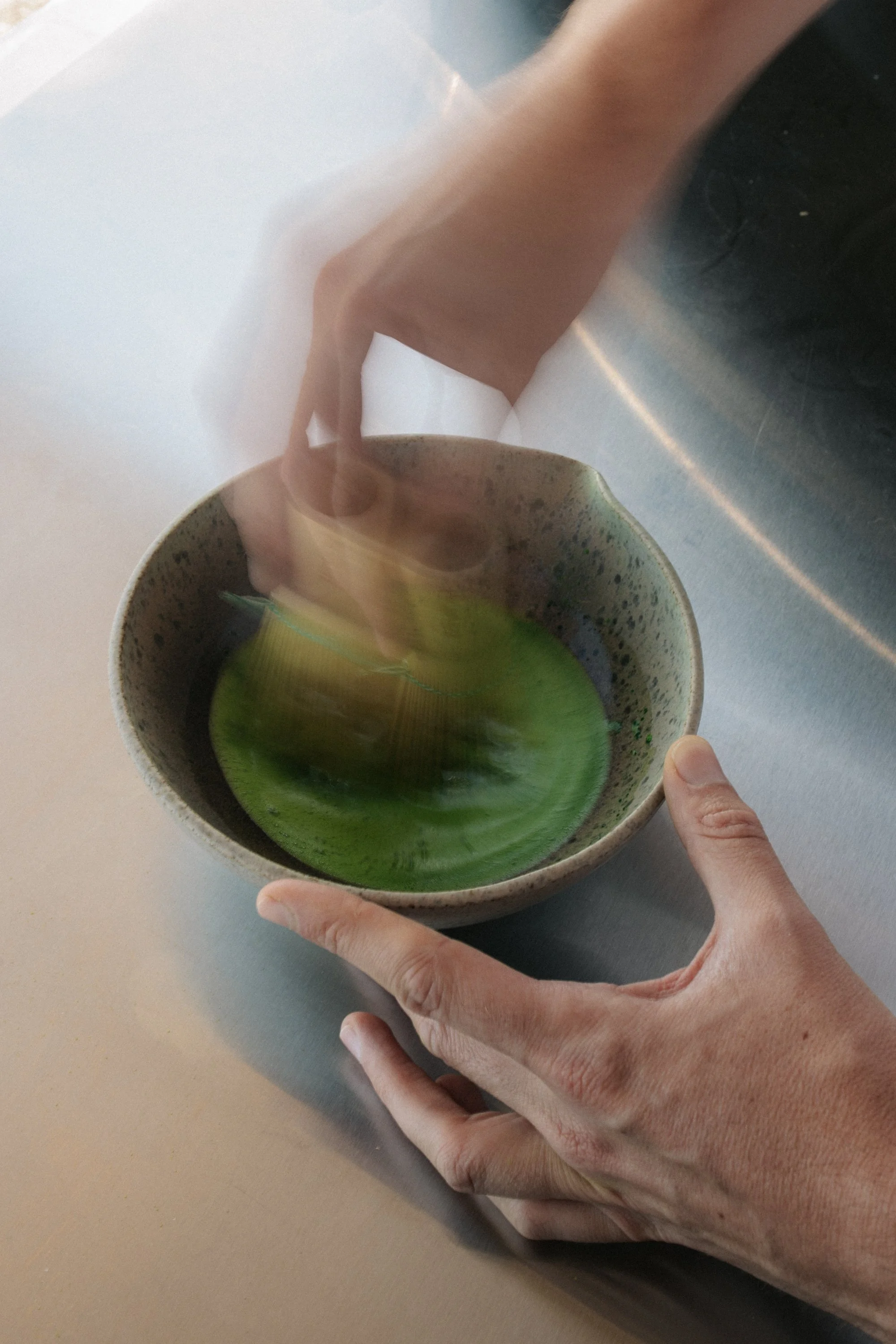 Matcha in a matcha bowl being whisked by a bamboo whisk