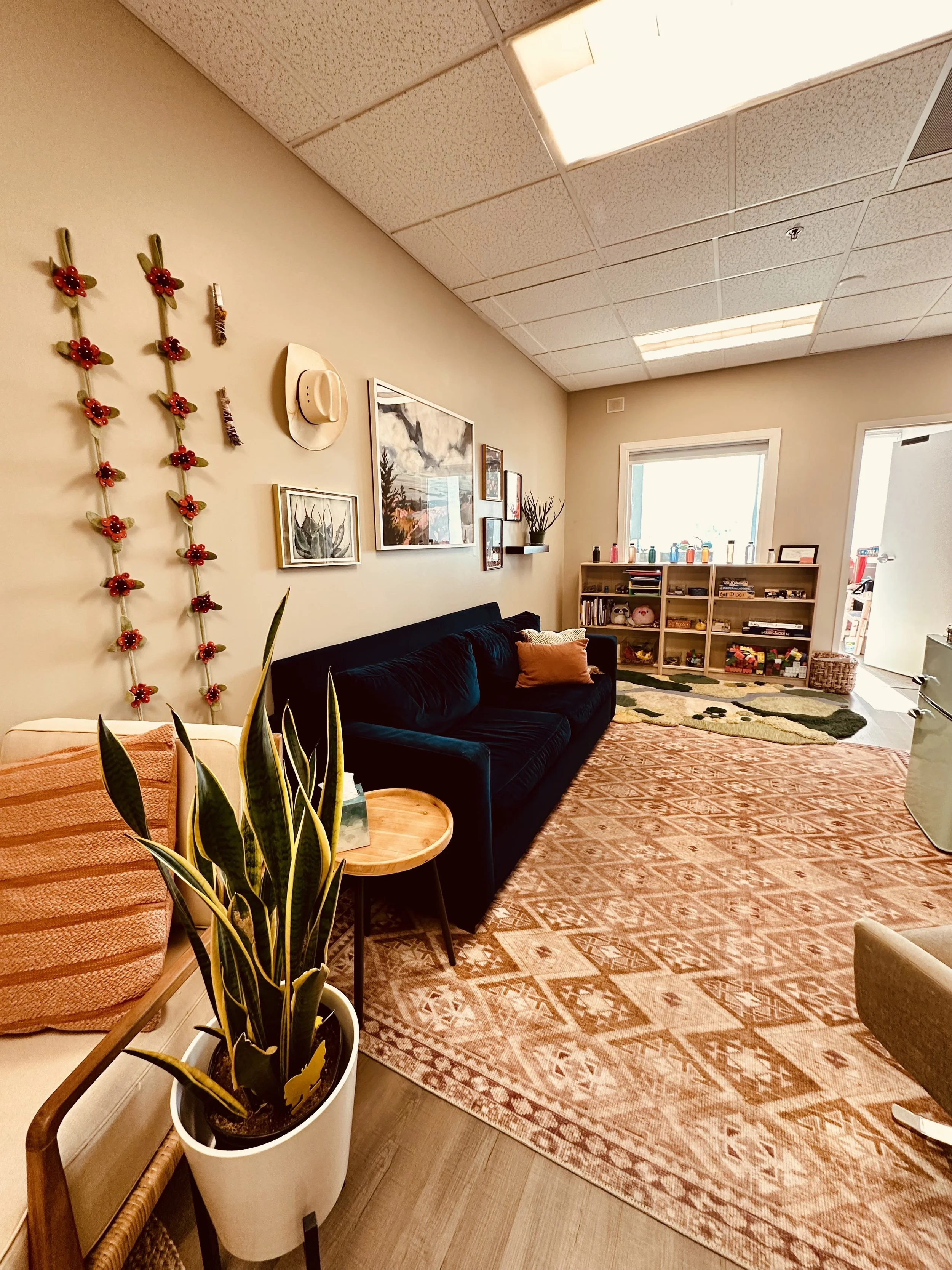 Gallery wall with a desert theme with a blue couch underneath. Bookshelves on adjoining wall with toys and books. Warm colored rug covers the floor.