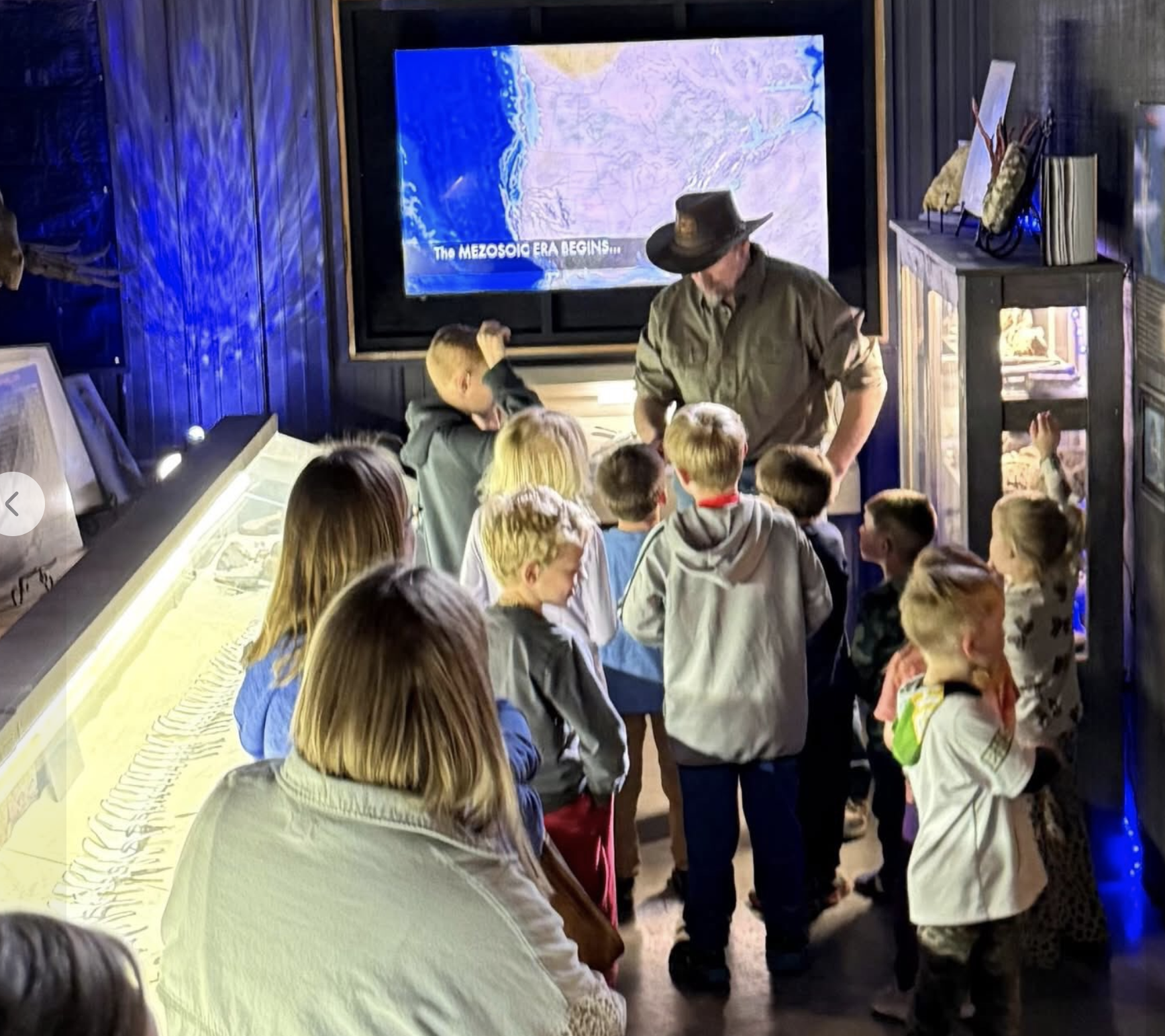 A black and white skeletal diagram of a dinosaur, possibly a Velociraptor, displayed on a black background.