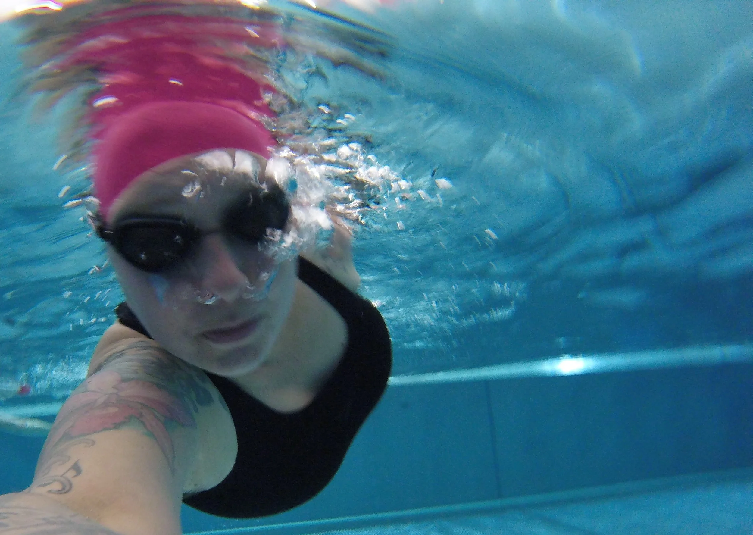 Schwimmerin unter Wasser Luftblasen Goggles Badekappe