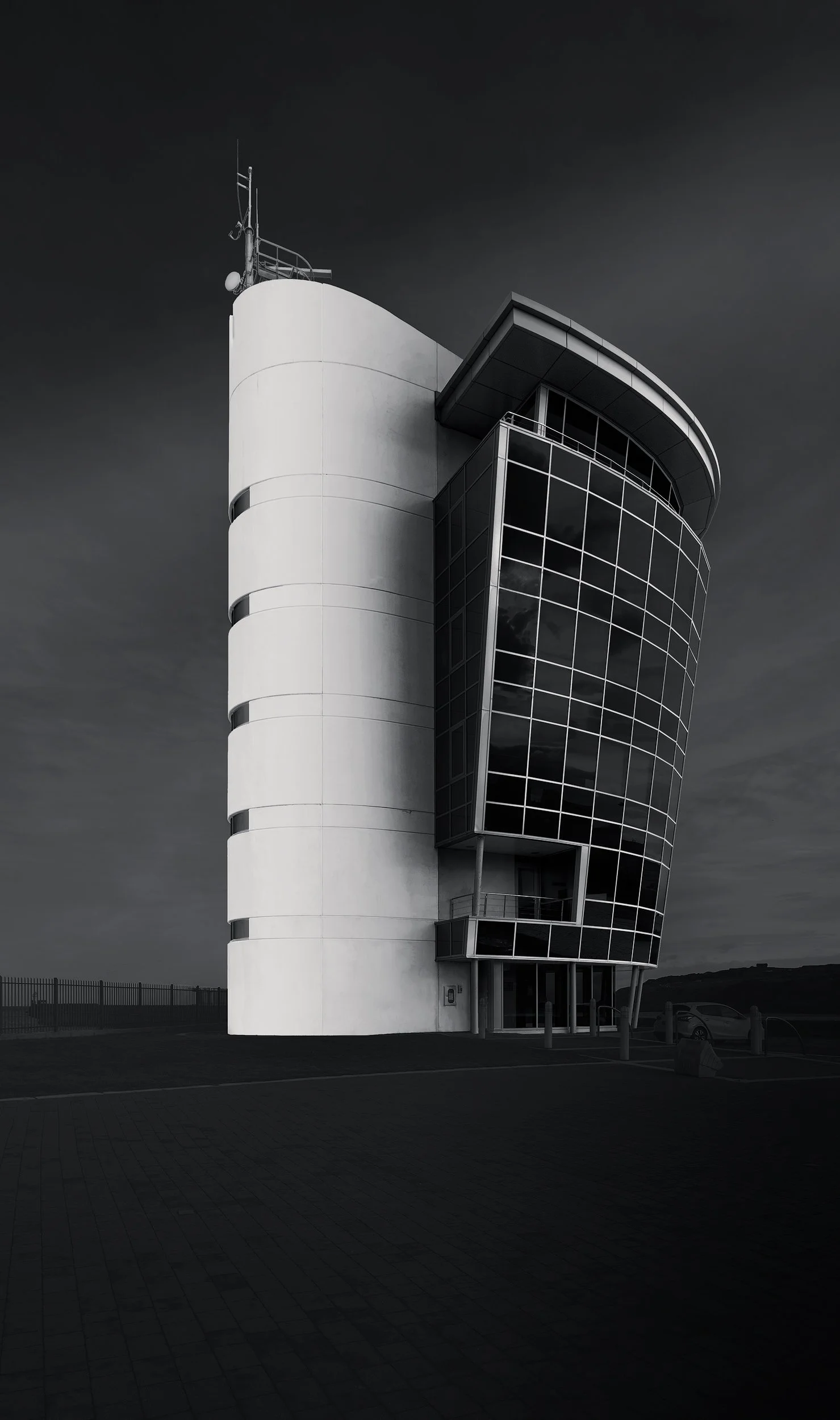 Contemporary maritime architecture in Aberdeen, Scotland: A dramatic monochromatic study of the Marine Operations Centre, designed by Halliday Fraser Munro. This vertical photograph captures the building’s unique nautical form, featuring a sleek whit