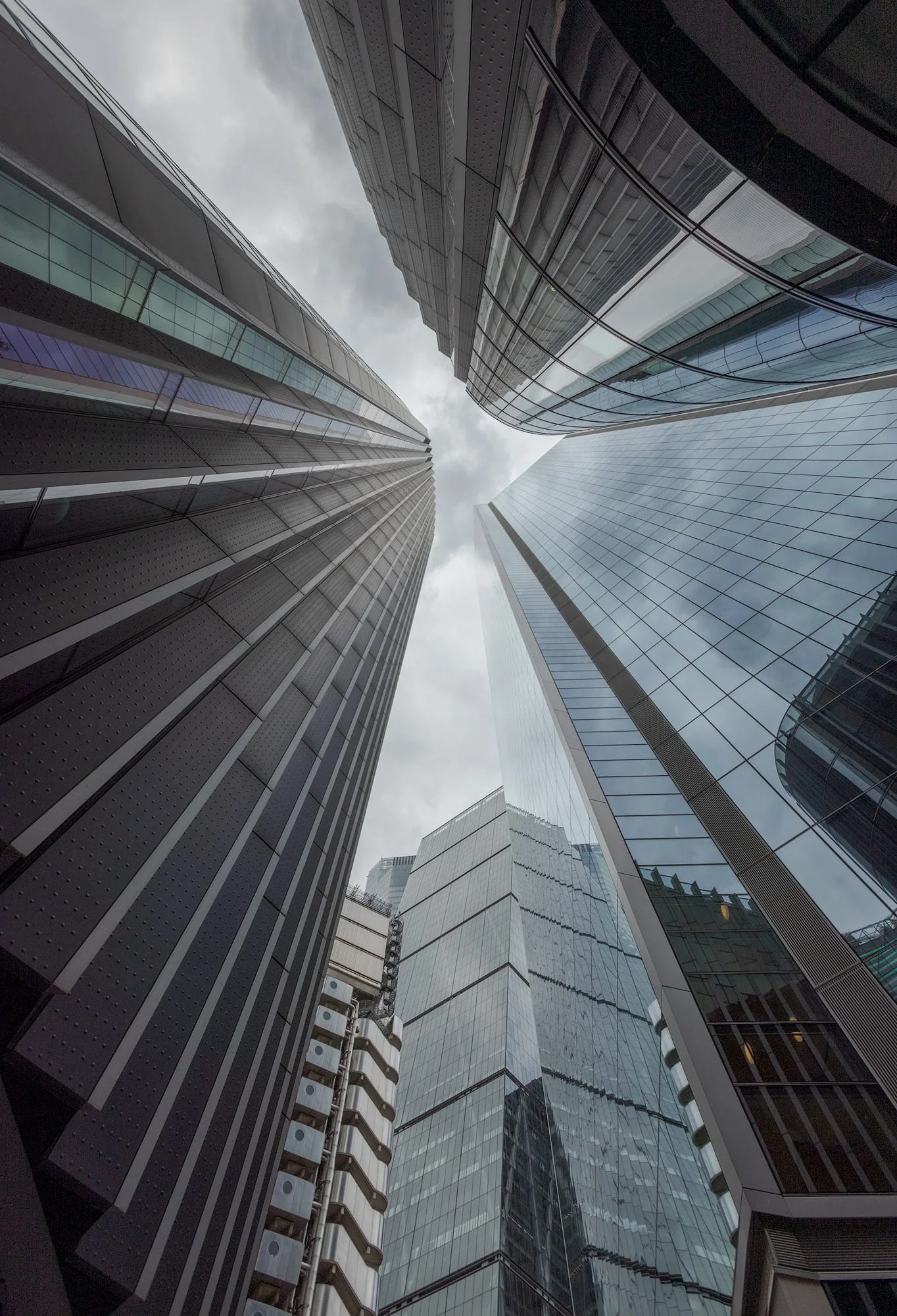 [architecture] [uk] [london] [colour] Upward through London's financial district, Leadenhall Building, Scalpel and Lloyd's converging against a clouded sky. Architectural Photography by Jim Scott.
