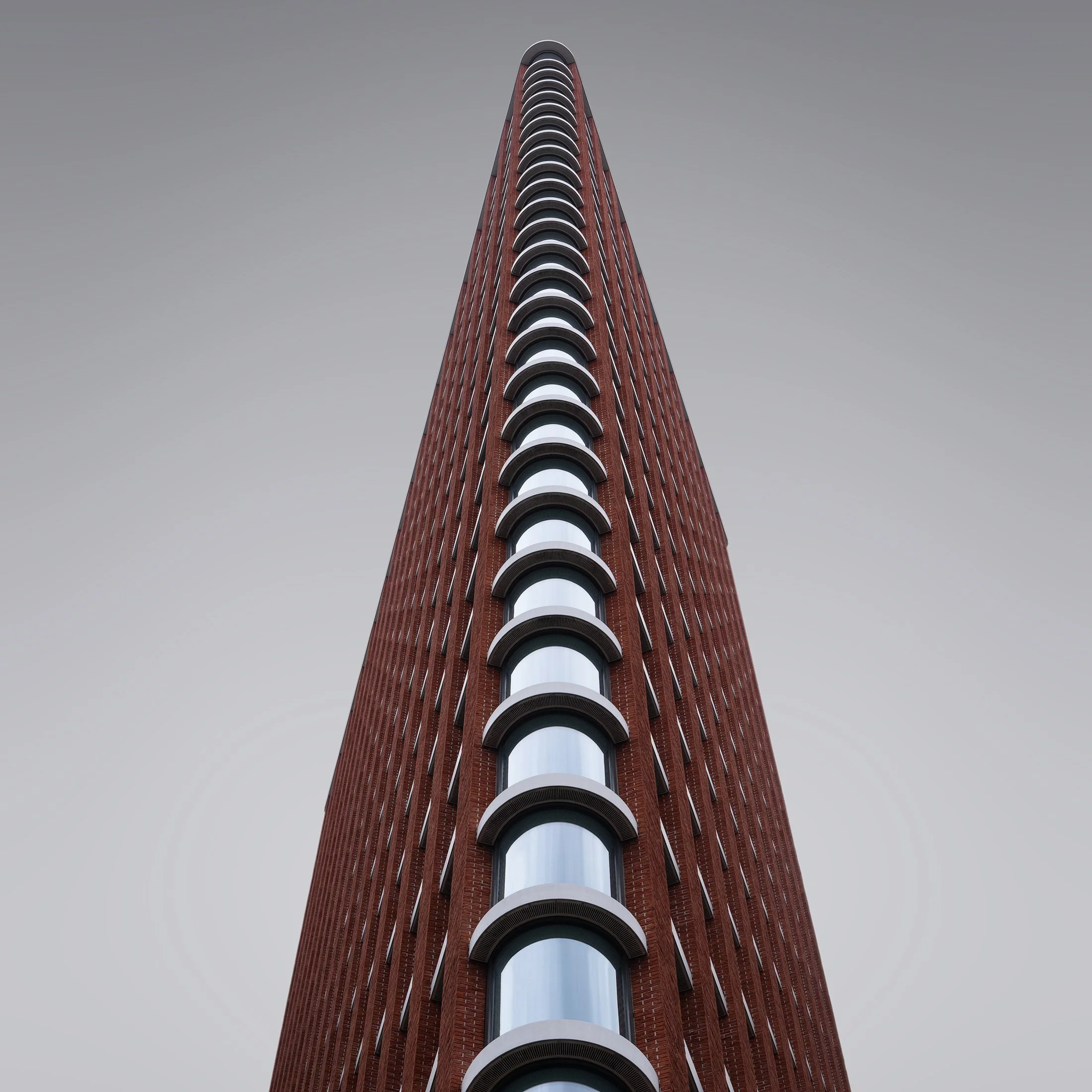 [architecture] [uk] [london] [colour] Urbanest Vauxhall London, stacked curved glass balconies set into rich red brick tapering sharply to a fine apex. Architectural Photography by Jim Scott. 