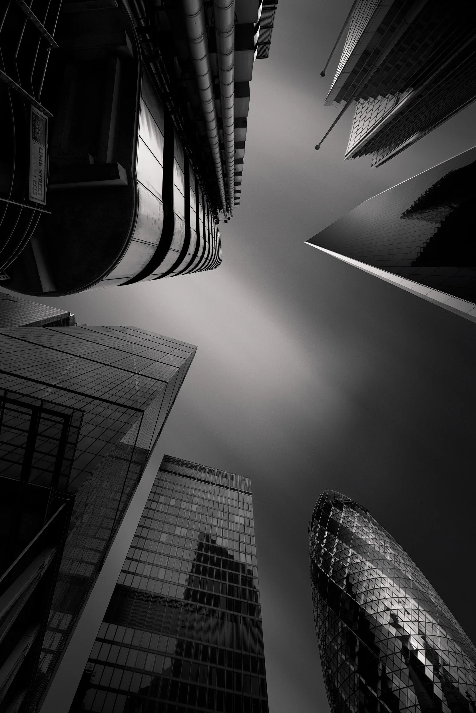 Contemporary skyscraper architecture in the City of London: A dramatic monochromatic including the Lloyd's Building, The Cheesegrater, The Gherkin, Willis Towers Watson and The Scalpel from Lime Street. This extreme upward perspective captures the de