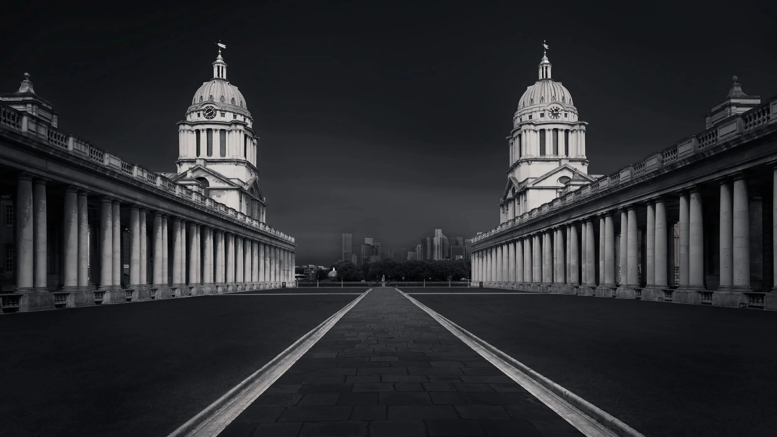 [architecture] [uk] [london] [blackandwhite] [panoramic] Royal Naval College Greenwich, twin Baroque domes and long colonnades converging to a central axis under a dark sky. Architectural Photography by Jim Scott.