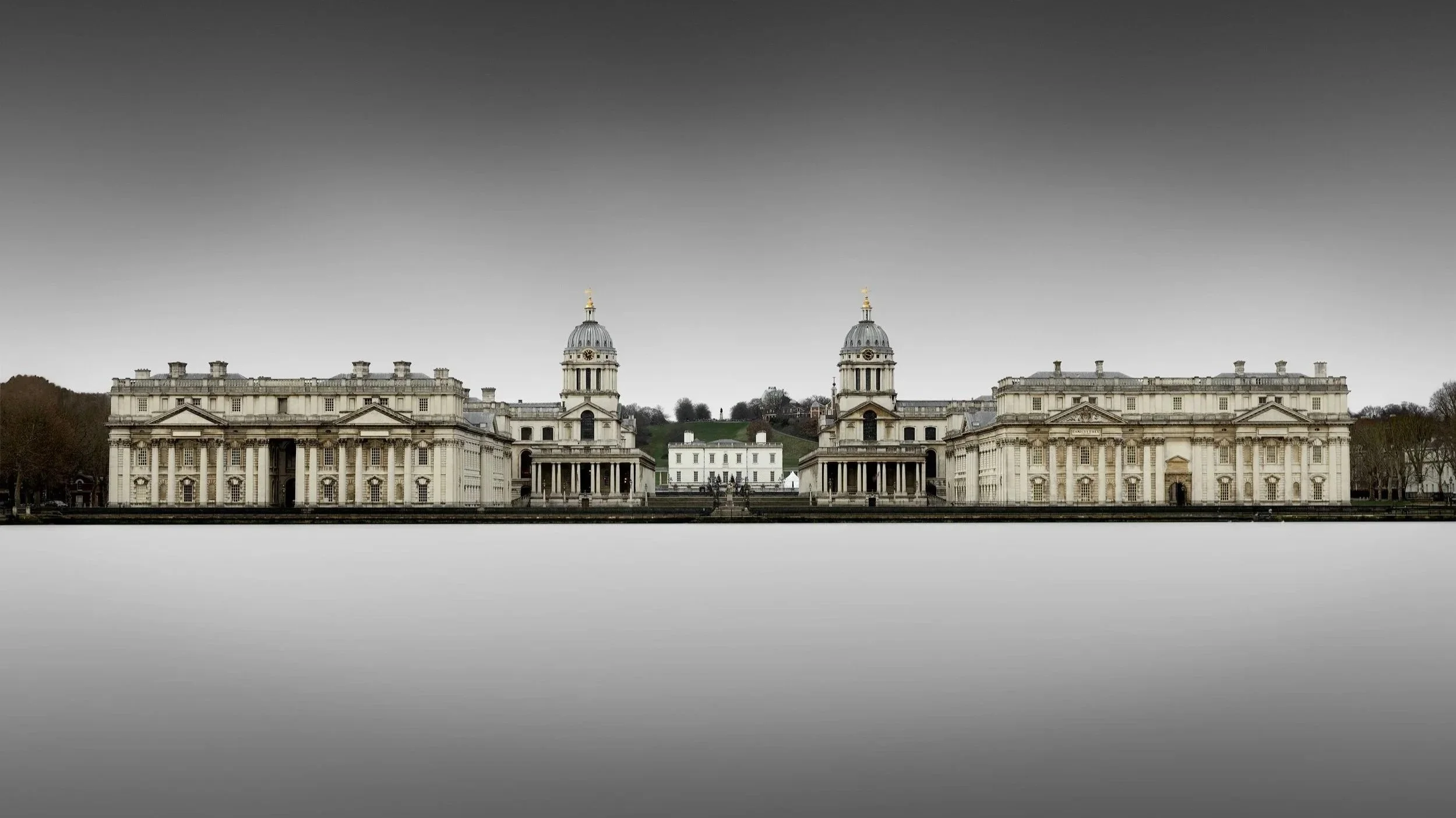 [architecture] [uk] [london] [colour] [panoramic] Symmetrical long exposure of Old Royal Naval College Greenwich, twin Baroque domes rising above a silken white Thames. Architectural Photography by Jim Scott.