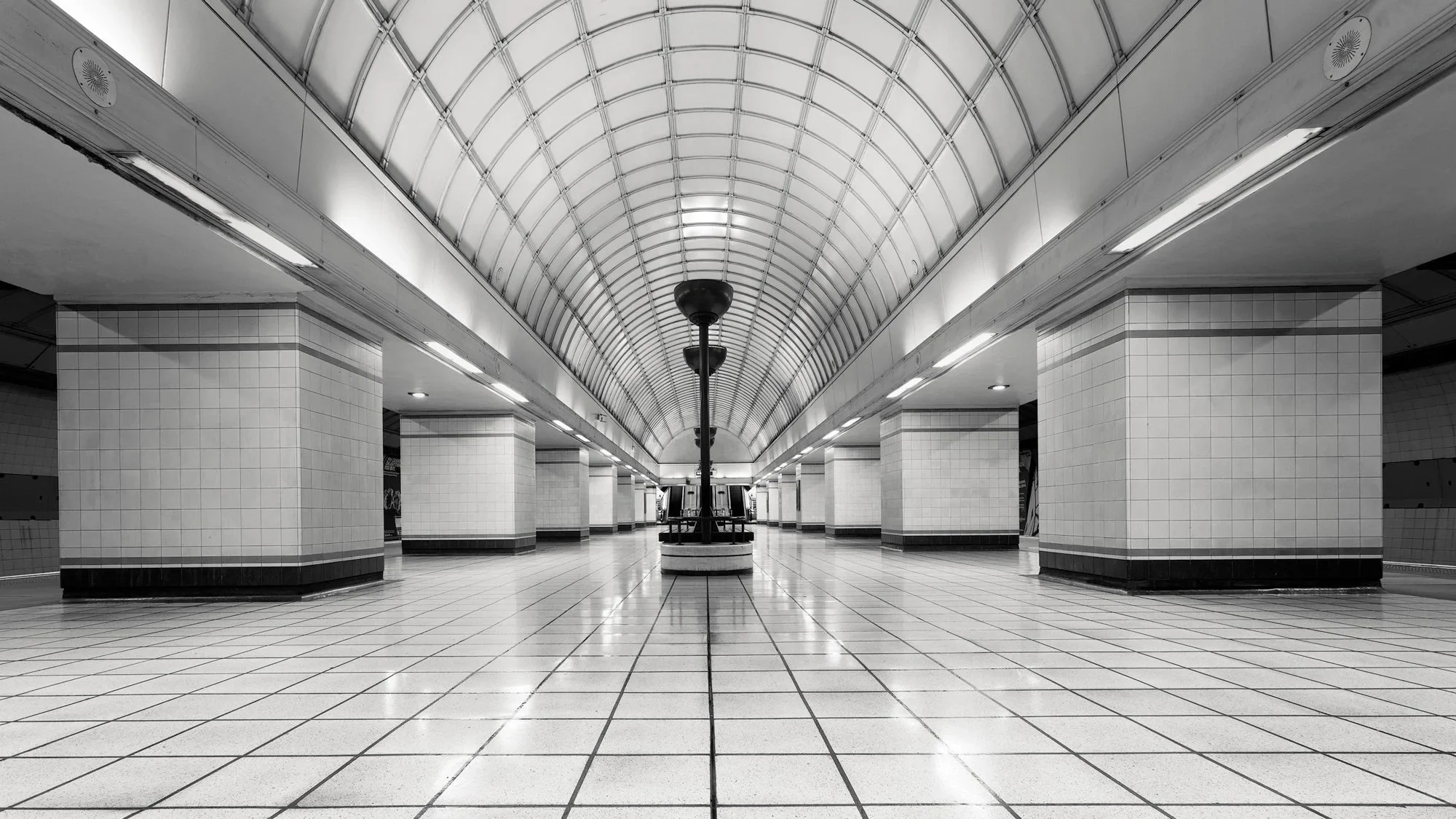 [architecture] [uk] [london] [blackandwhite] [panoramic] [internal] Gants Hill Underground Station London, Holden Art Deco barrel vaulted concourse with central lamppost, perfect symmetrical interior. Architectural Photography by Jim Scott.