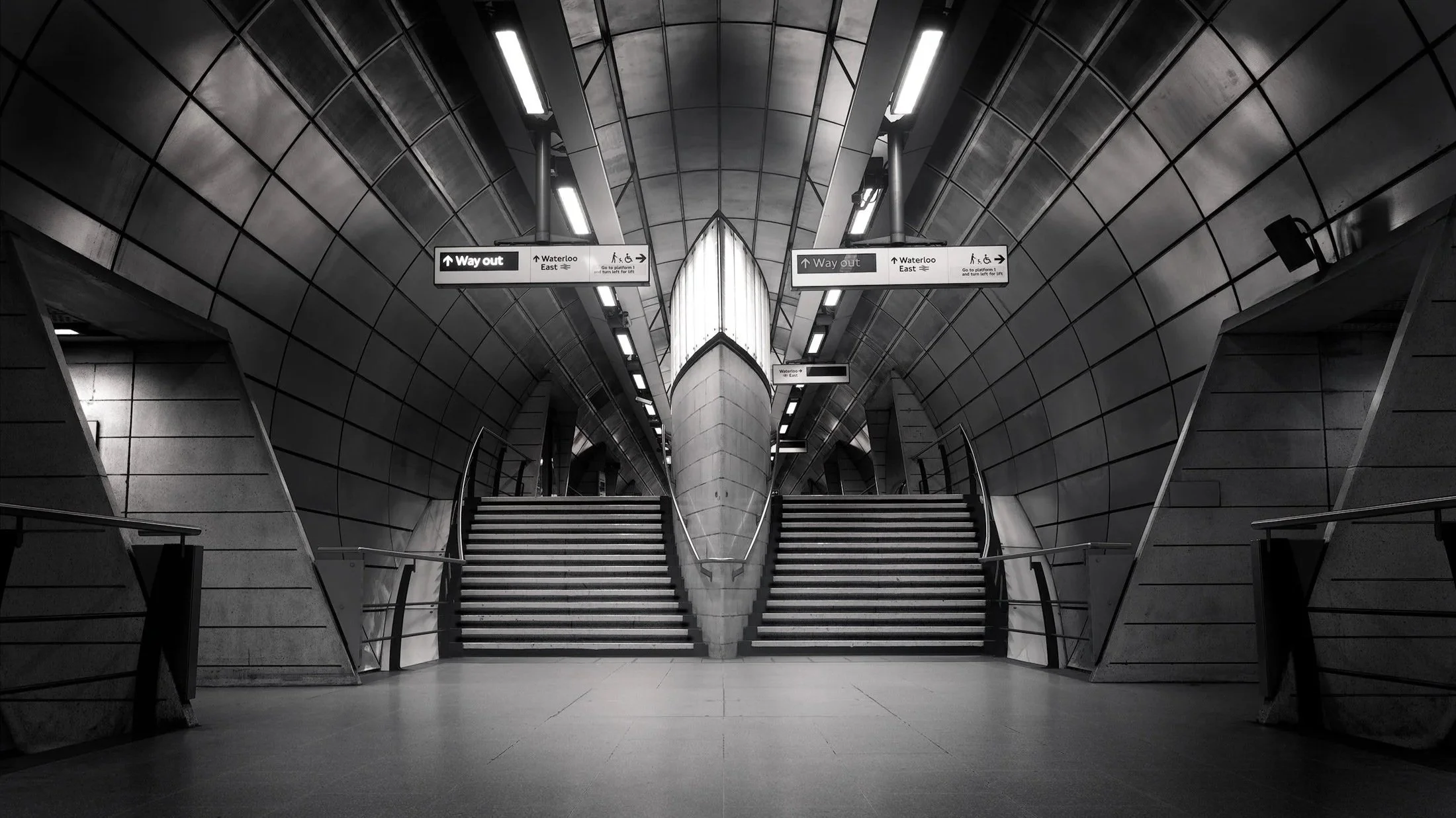 [architecture] [uk] [london] [blackandwhite] [panoramic] Southwark Underground station London, symmetrical steel-clad barrel vault lit by fluorescent strips receding to a point. Architectural Photography by Jim Scott.