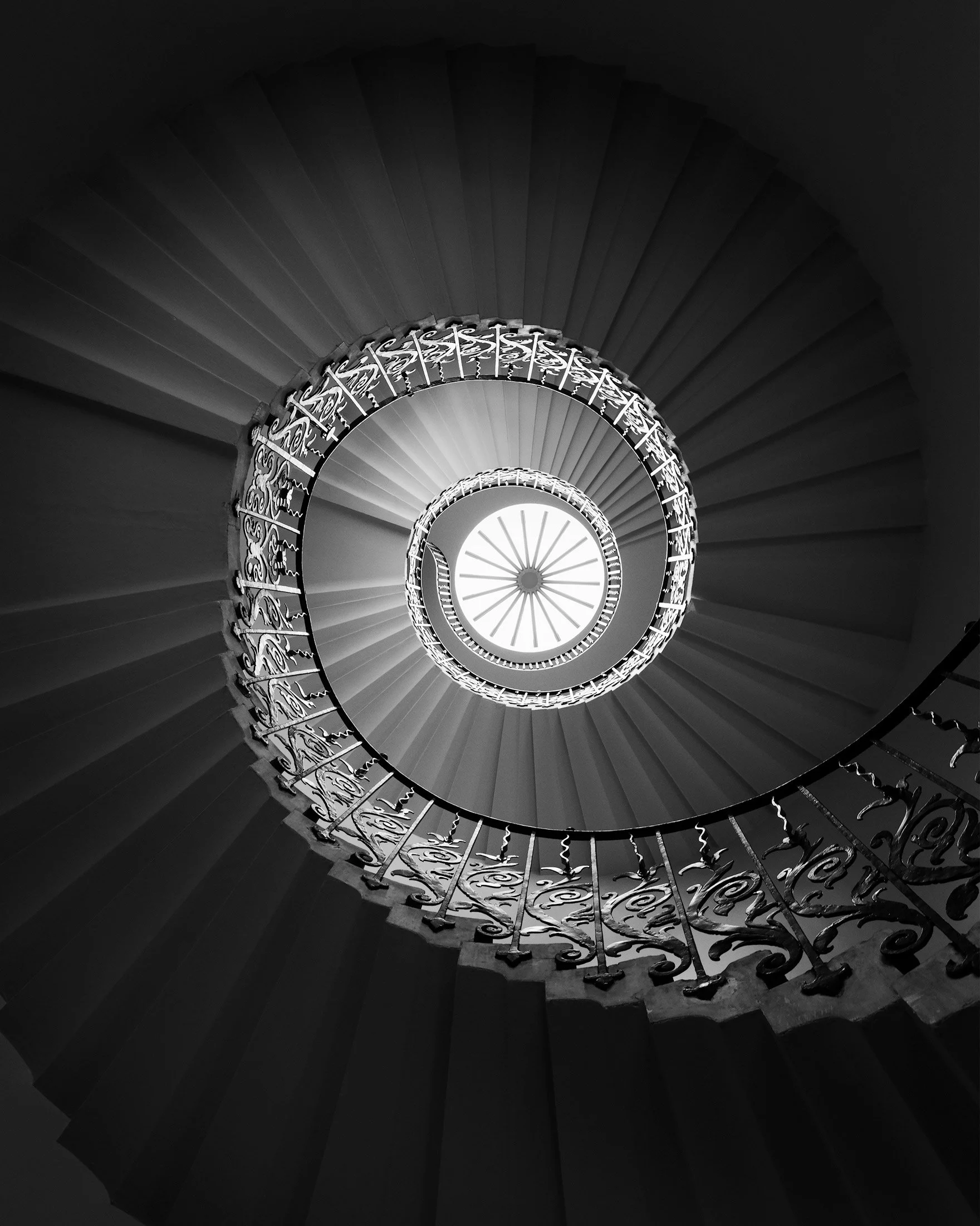 Seventeenth-century Palladian architecture in Greenwich, London: A dramatic monochromatic study of the Tulip Stairs within the Queen’s House, designed by Inigo Jones. This bottom-up architectural photograph captures the elegant, self-supporting canti