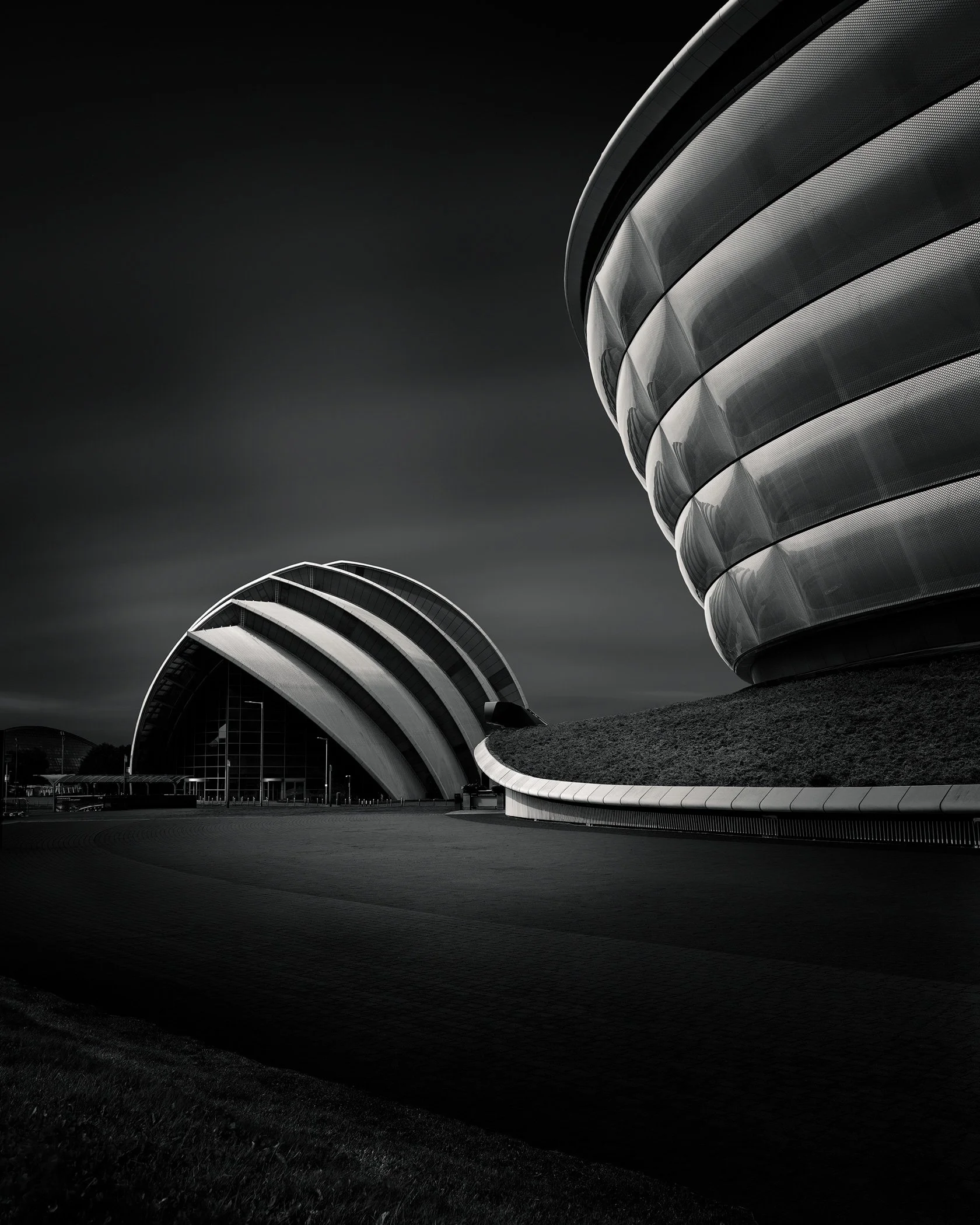 [architecture] [uk] [glasgow] [blackandwhite] OVO Hydro and Armadillo Glasgow at night, ribbed titanium dome and scalloped steel shell contrasted against dark sky. Architectural Photography by Jim Scott.