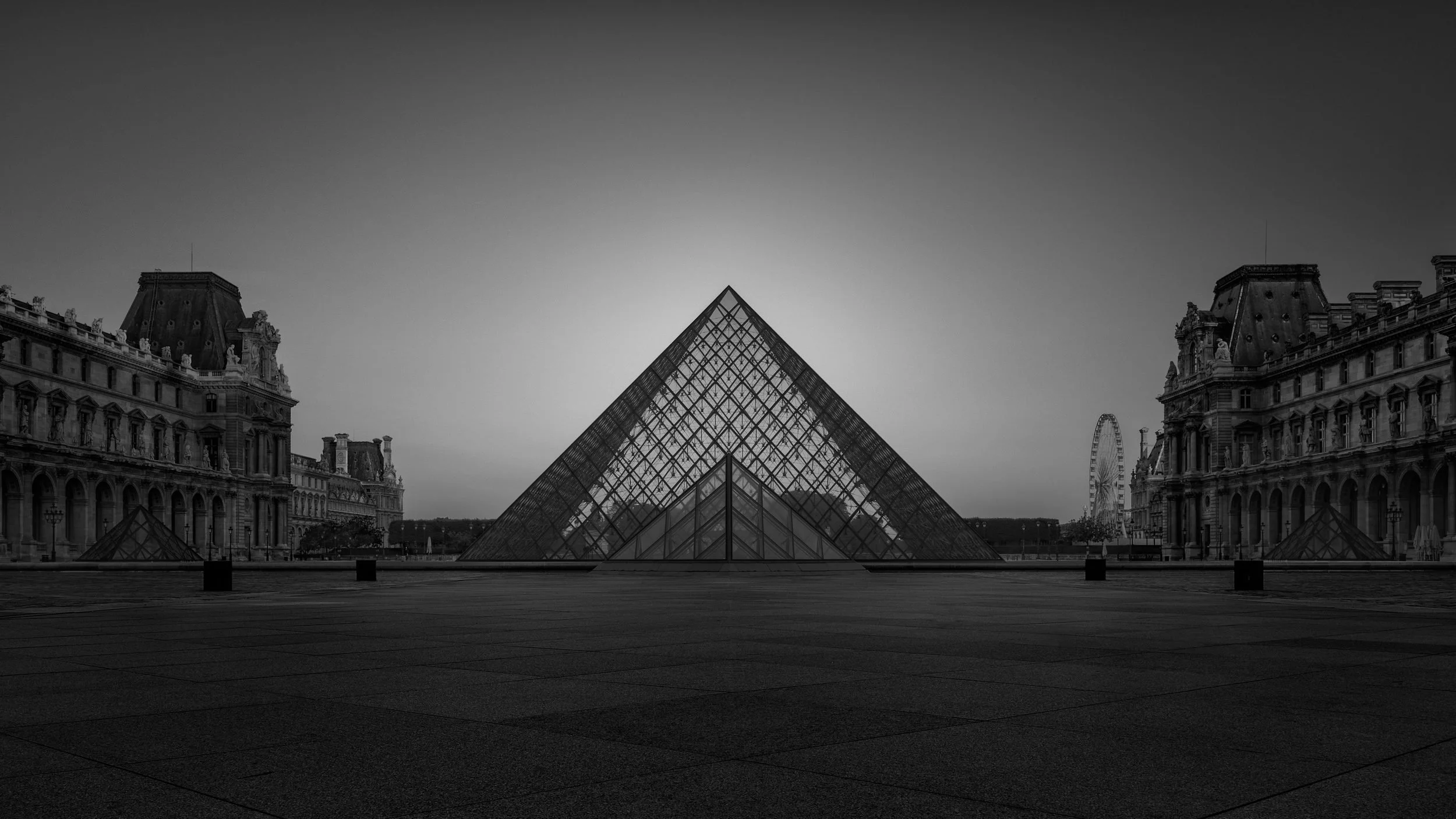 [architecture] [europe] [paris] [blackandwhite] [panoramic] Louvre Museum courtyard Paris, I.M. Pei's glass pyramid centred between the historic stone palace wings. Architectural Photography by Jim Scott.
