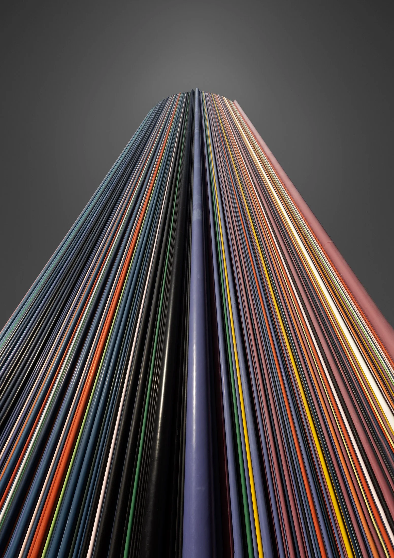 Contemporary monumental sculpture in La Défense, Paris: A dramatic study of Le Moretti, designed by Raymond Moretti. This architectural photograph captures the 32-metre chimney stack clad in 672 fibreglass tubes of varying colours and diameters. The 