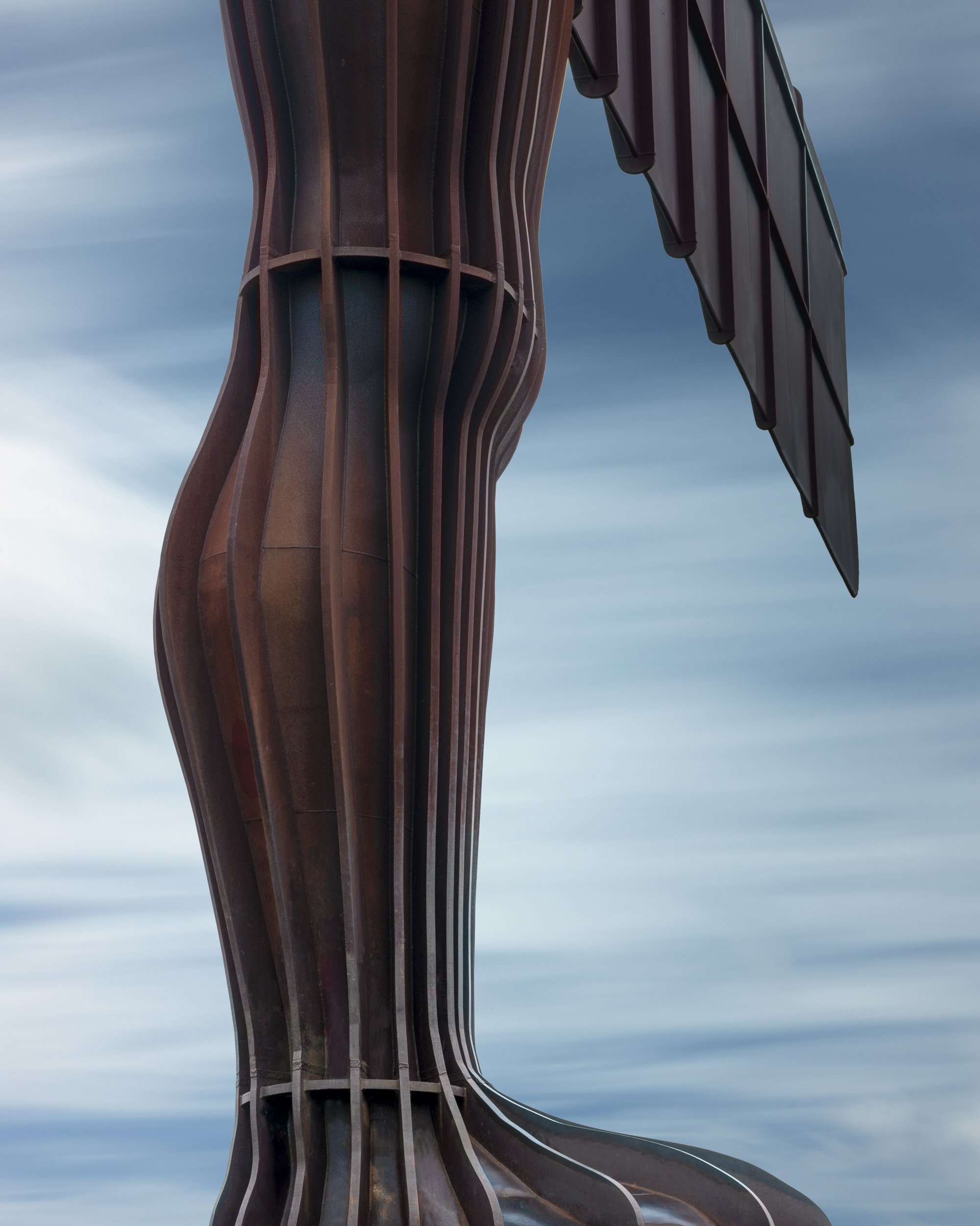 [architecture] [uk] [gateshead] [colour ] Angel of the North Gateshead close-up, Antony Gormley's steel sculpture body and wing against a pale blue sky. Architectural Photography by Jim Scott.