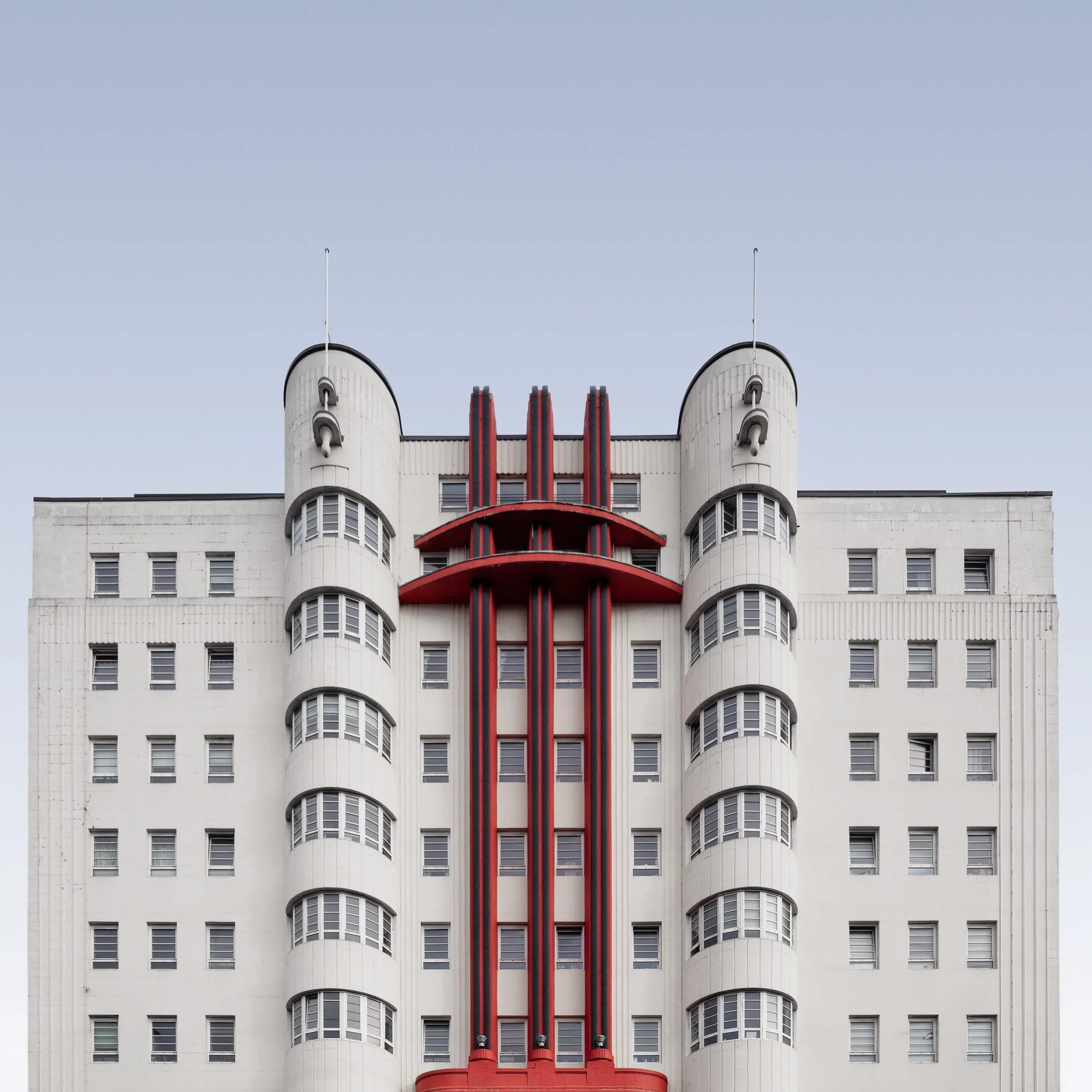 [architecture] [uk] [glasgow] [colour] [square] Beresford Building Glasgow, bold Art Deco tower with red vertical fins and cream cladding against a pale sky. Architectural Photography by Jim Scott.